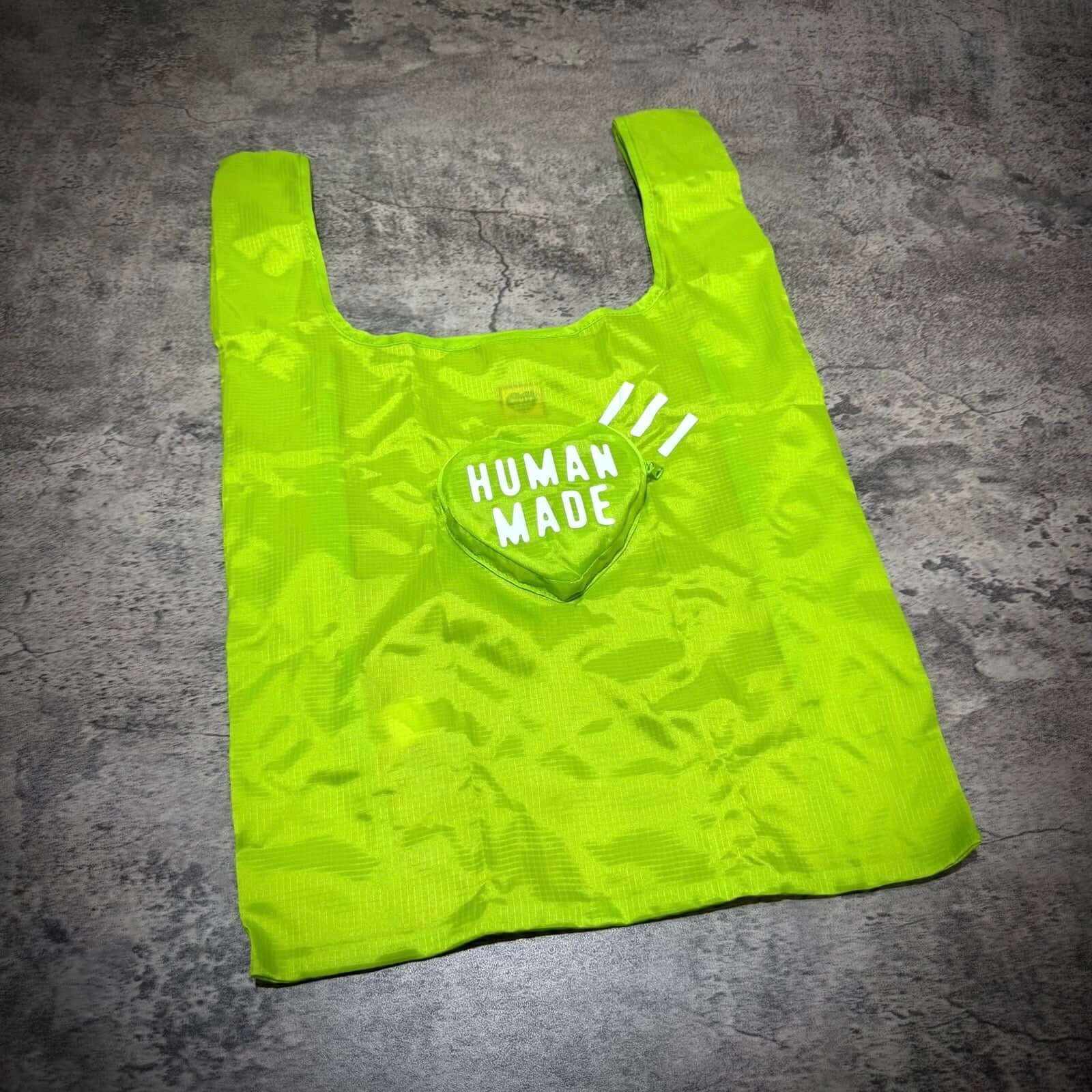 Human Made Heart Shopping Bag in bright green color displayed on a textured background.