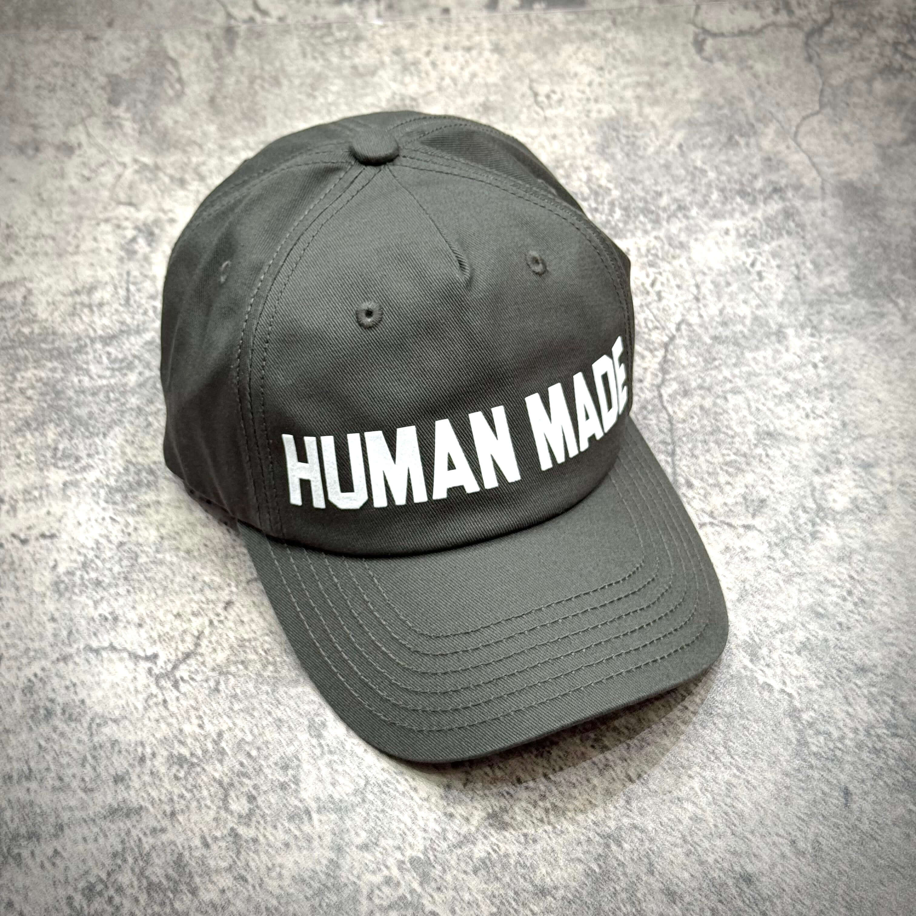 Human Made 5 Panel Twill Cap in gray with white text on the front, showcasing its stylish design.