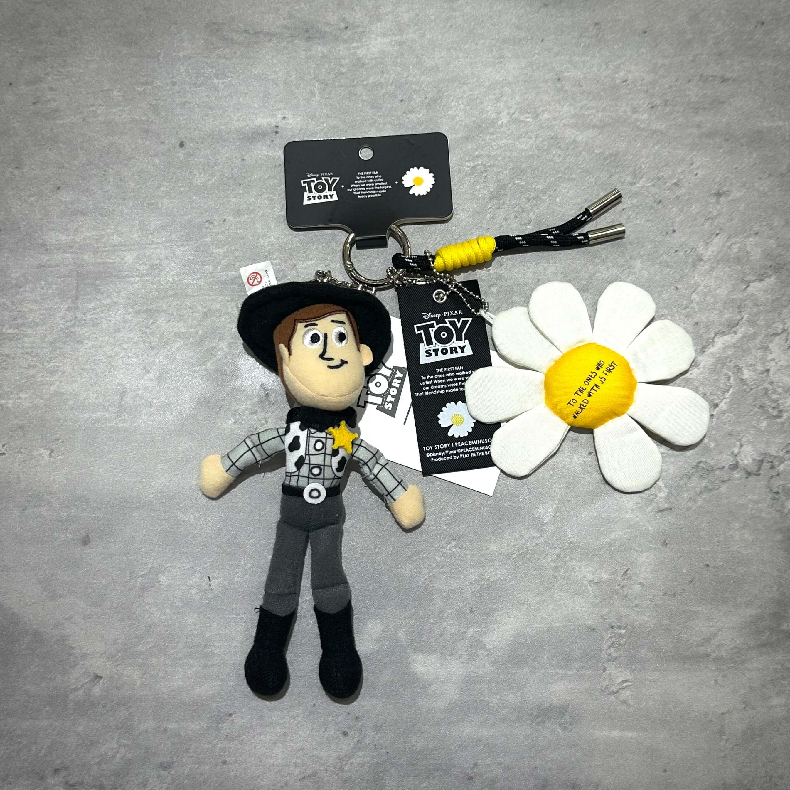 PEACEMINUSONE x Toy Story The First Fan - Plush Key Ring featuring a plush Woody character and flower keychain.