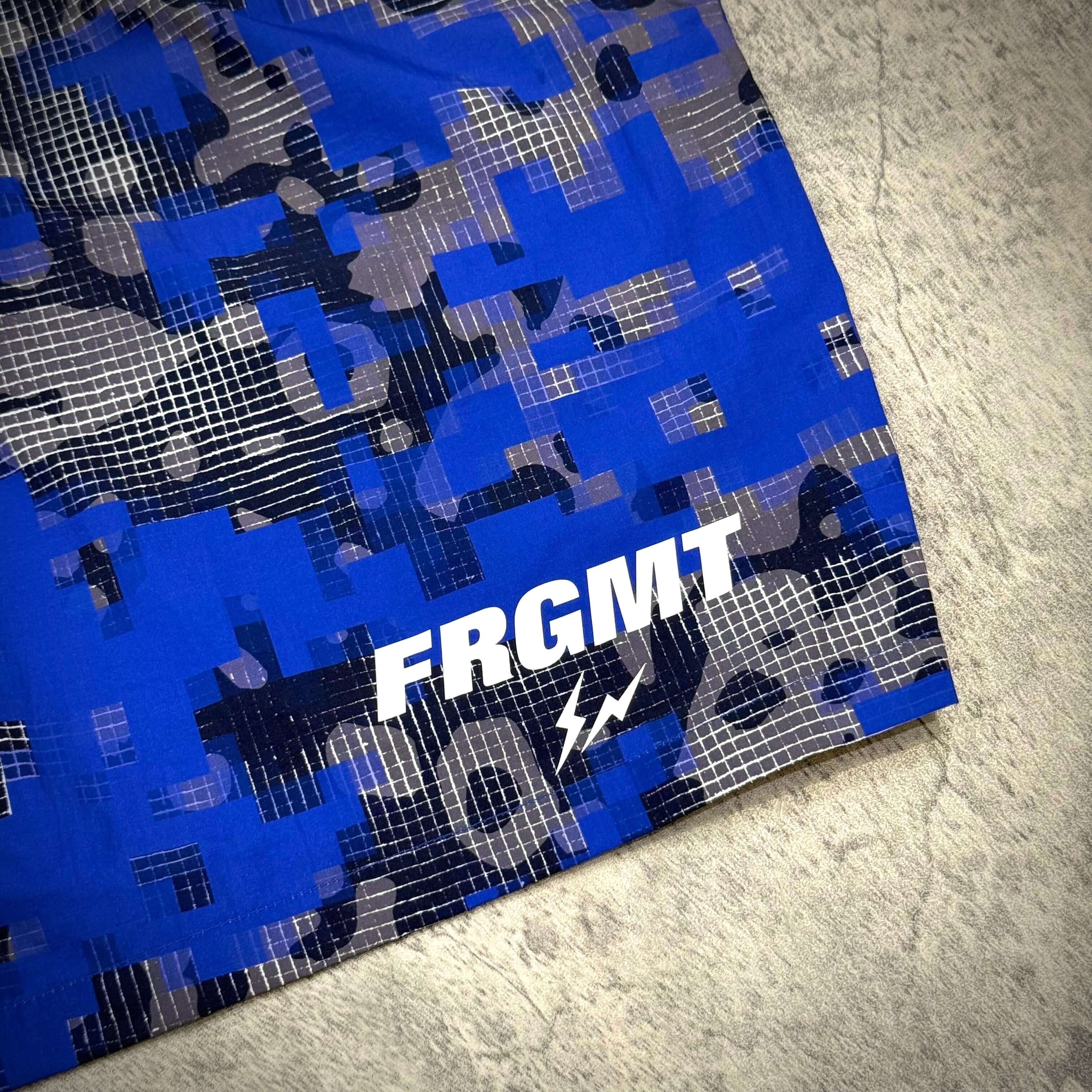 Fragment x FCRB Camouflage Nylon Shorts featuring blue digital camouflage pattern and FRGMT logo.
