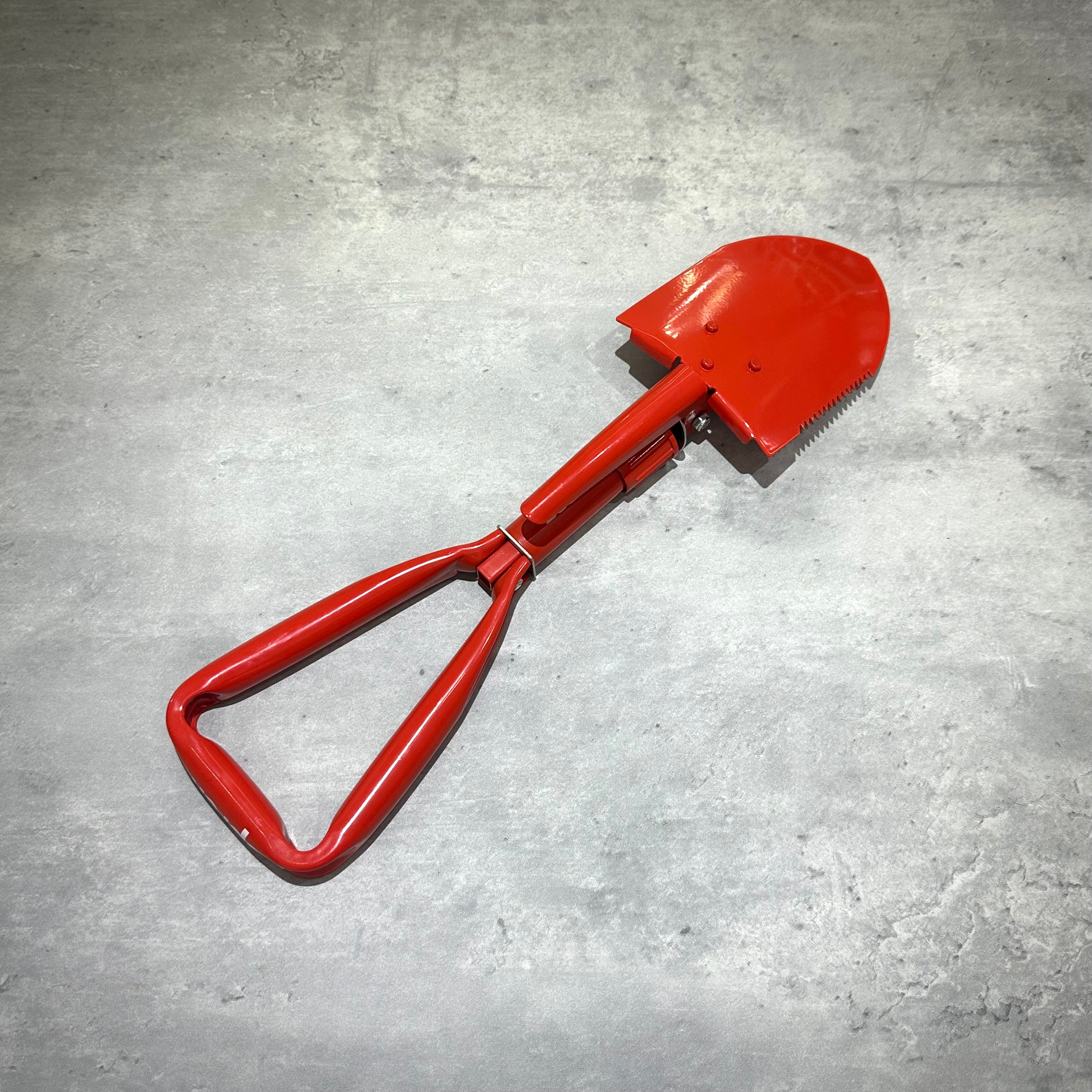 Supreme SOG Collapsible Shovel displayed on a gray surface, featuring a bright red color and unique straight blade design.
