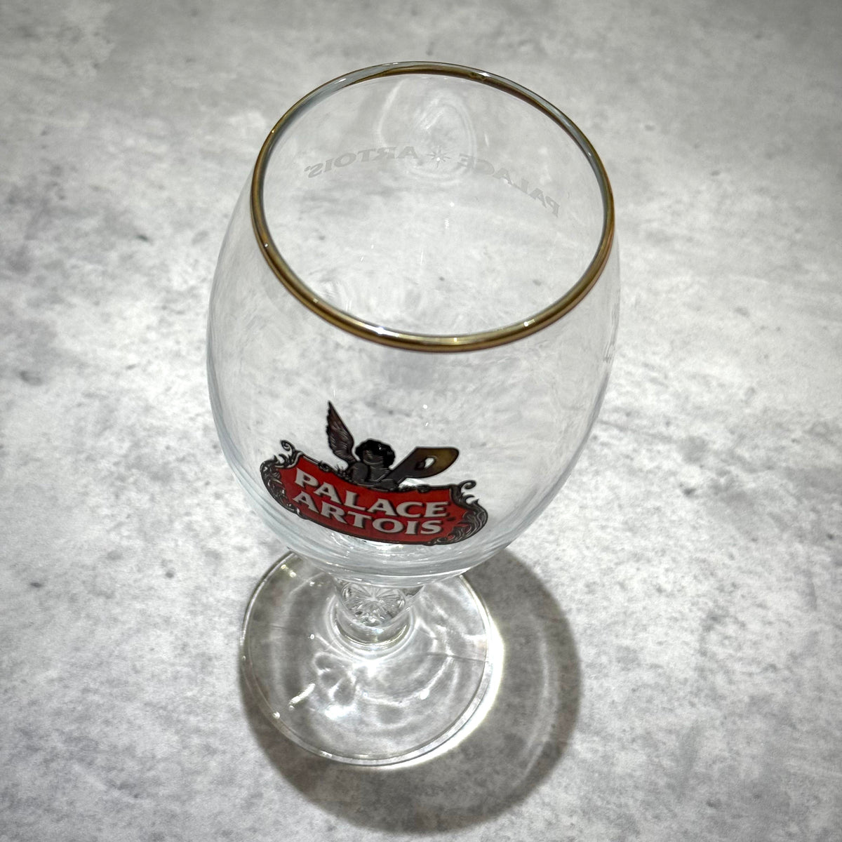 Palace x Stella Artois 500ML Pint Chalice - Clear showing logo and gold rim on a marble surface.