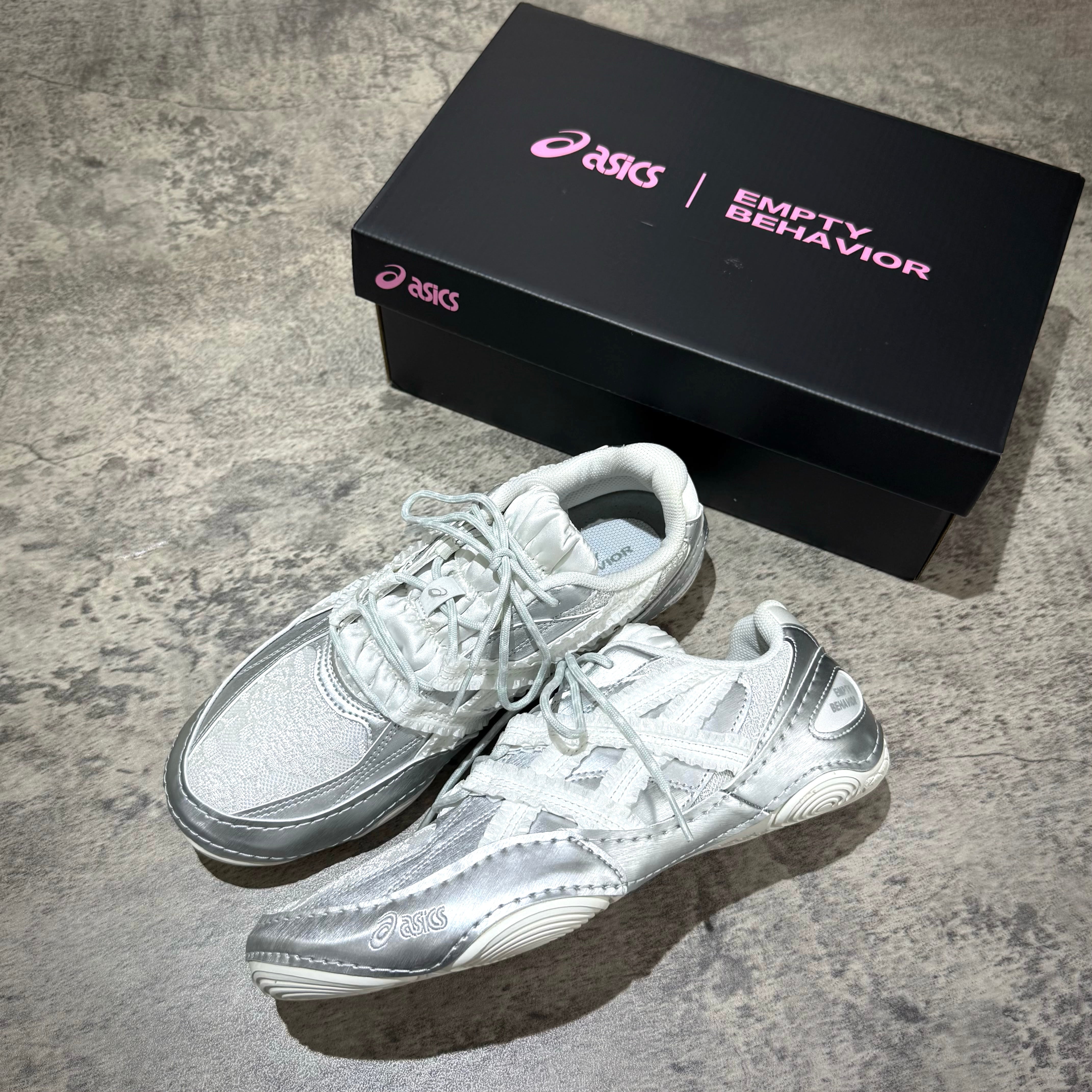 Asics x Empty Behavior Hypersync - Pure Silver White sneakers displayed with their box on a textured surface.