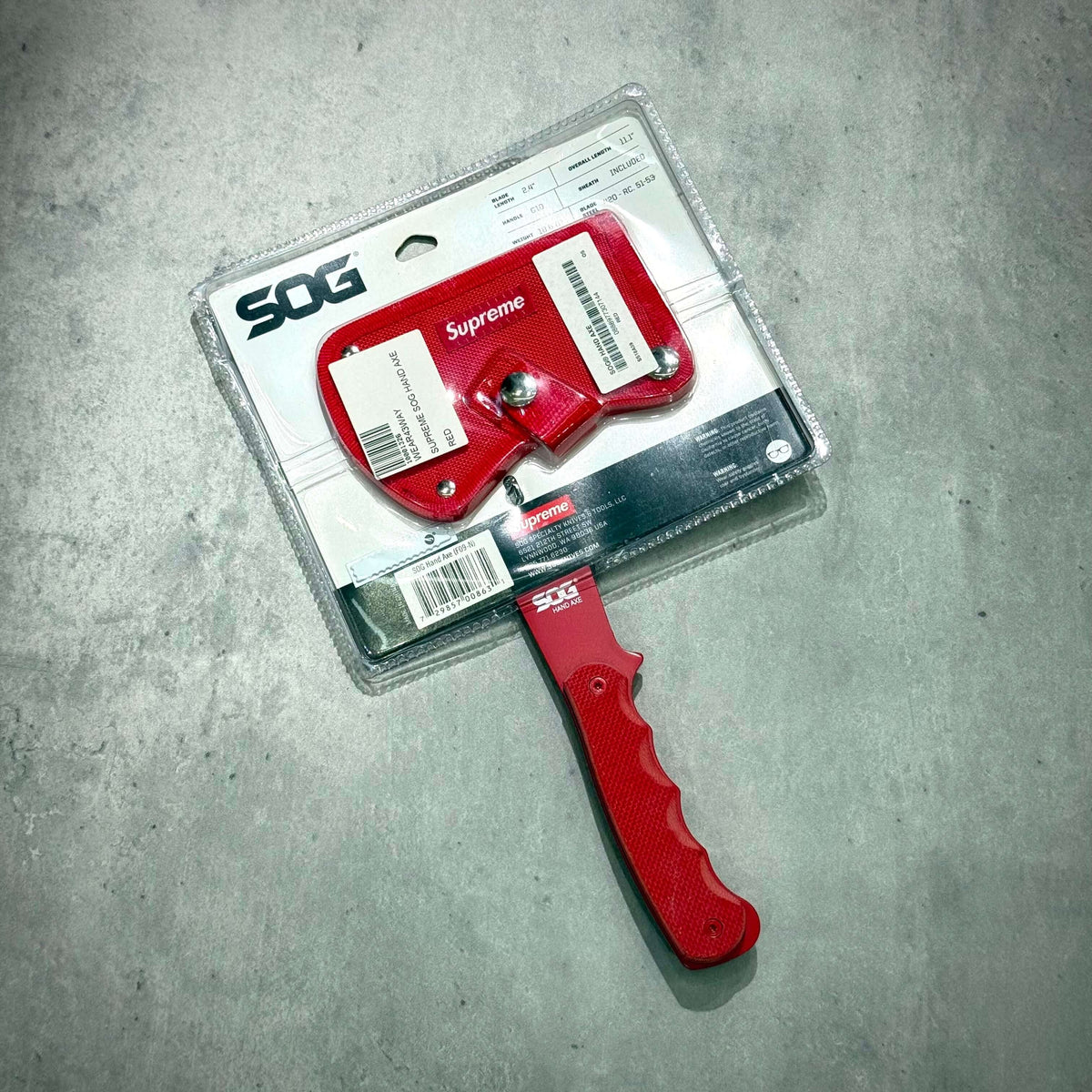 Supreme SOG Hand Axe - Red with packaging, showcasing the design and logo on the axe head.