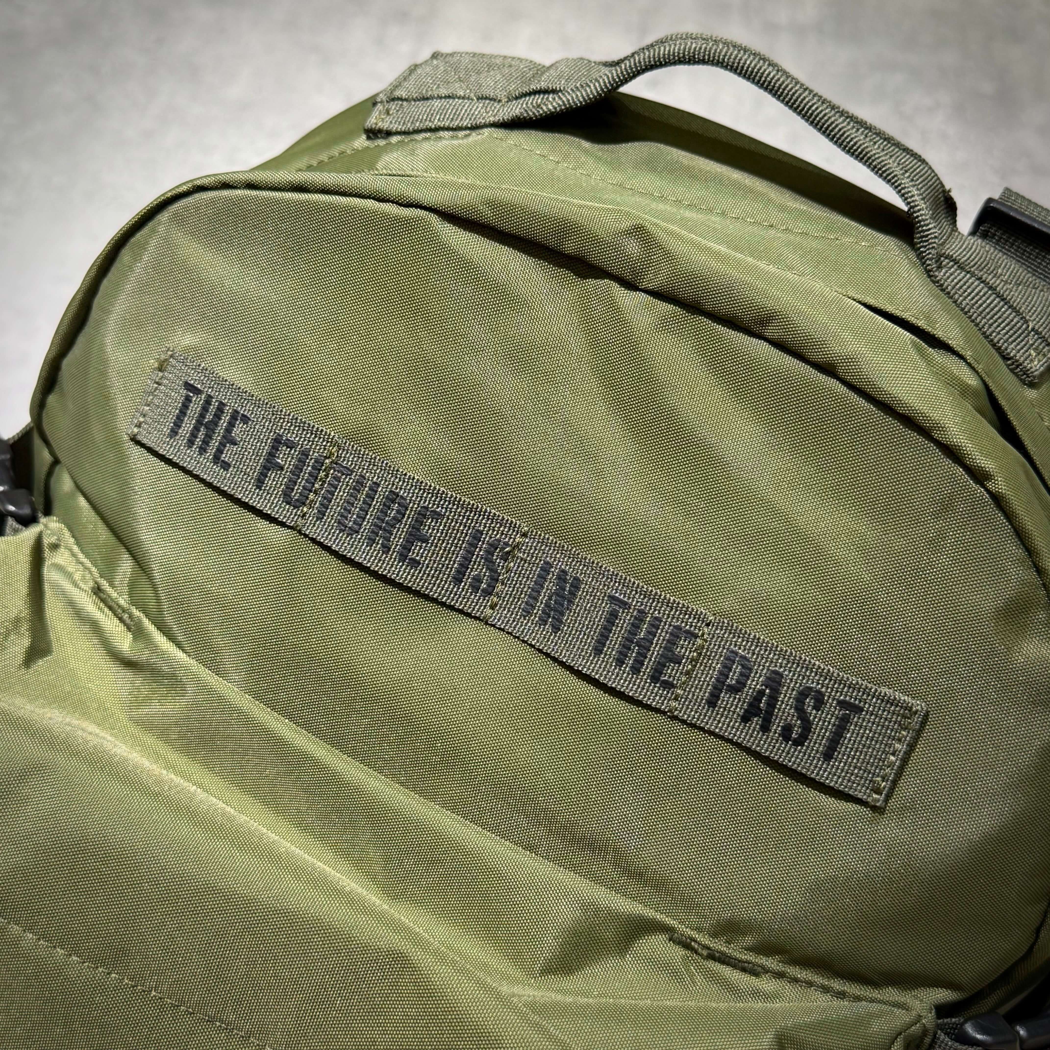Close-up of Human Made Military Backpack showcasing the bold phrase 'THE FUTURE IS IN THE PAST' on the front.