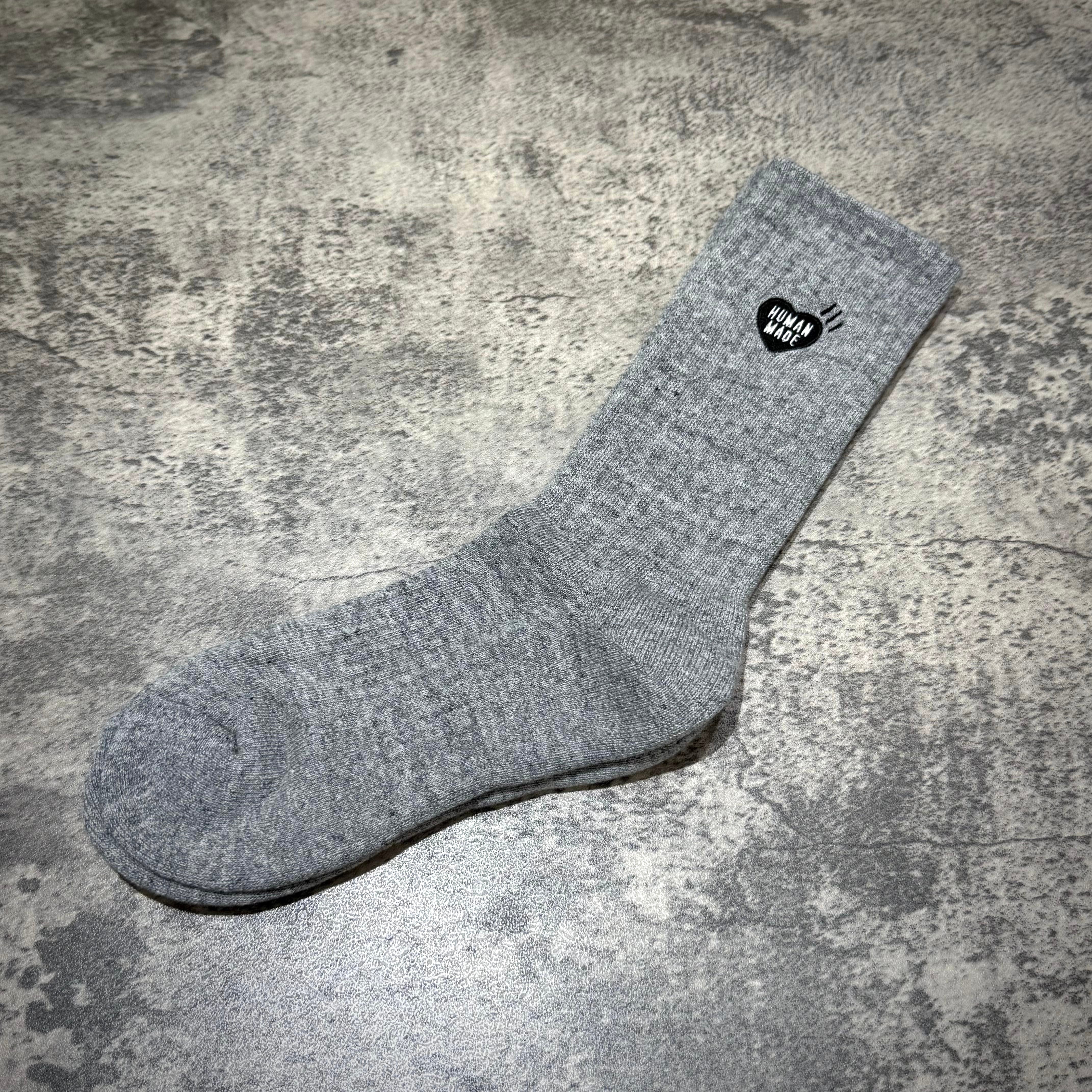 Human Made Pile Socks displayed on a textured surface, showcasing their unique design and logo.