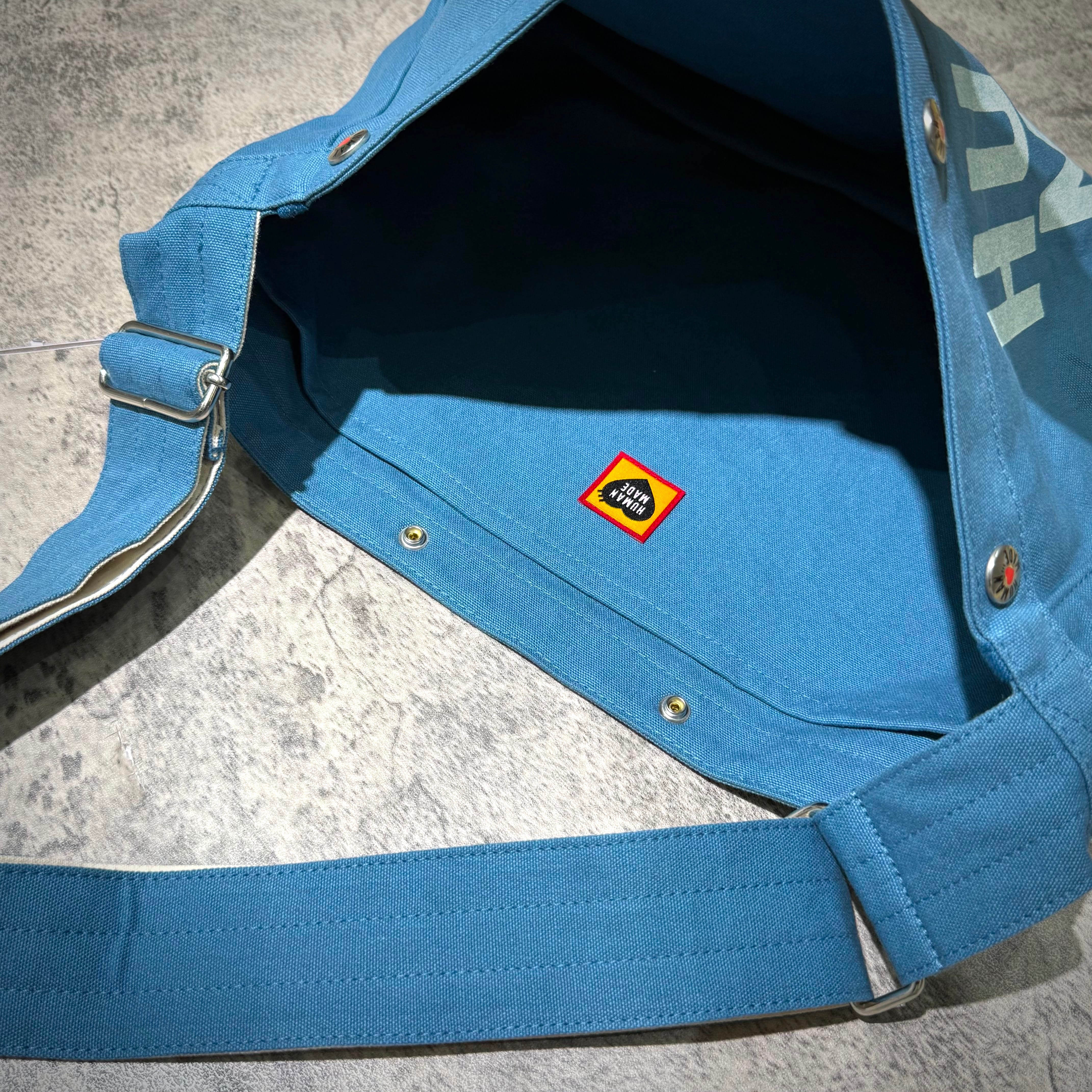 Interior view of Human Made Paper Boy Bag with branded label, showcasing its spacious design and quality craftsmanship.