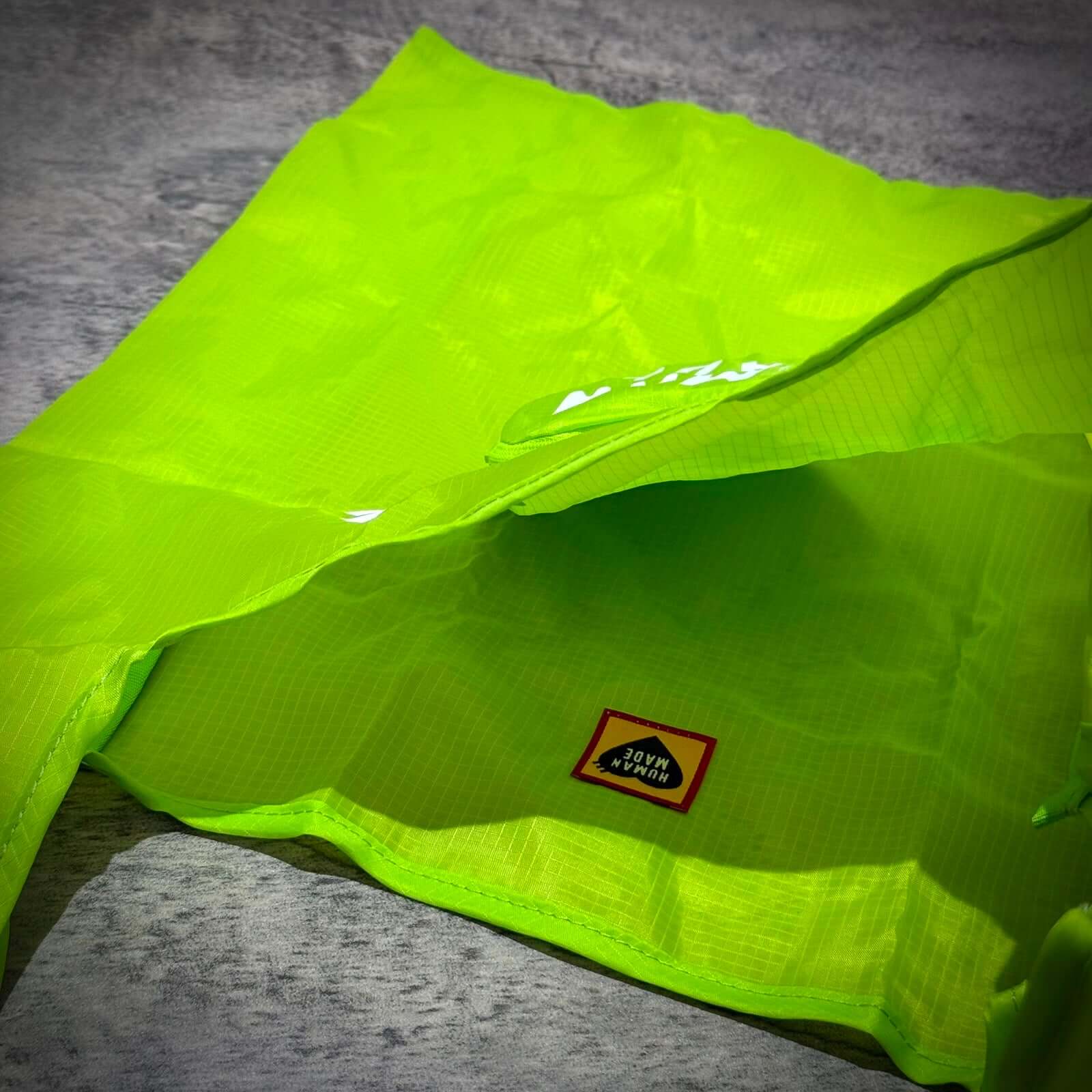 Human Made Heart Shopping Bag in vibrant neon green color showcasing the inner lining and brand label.