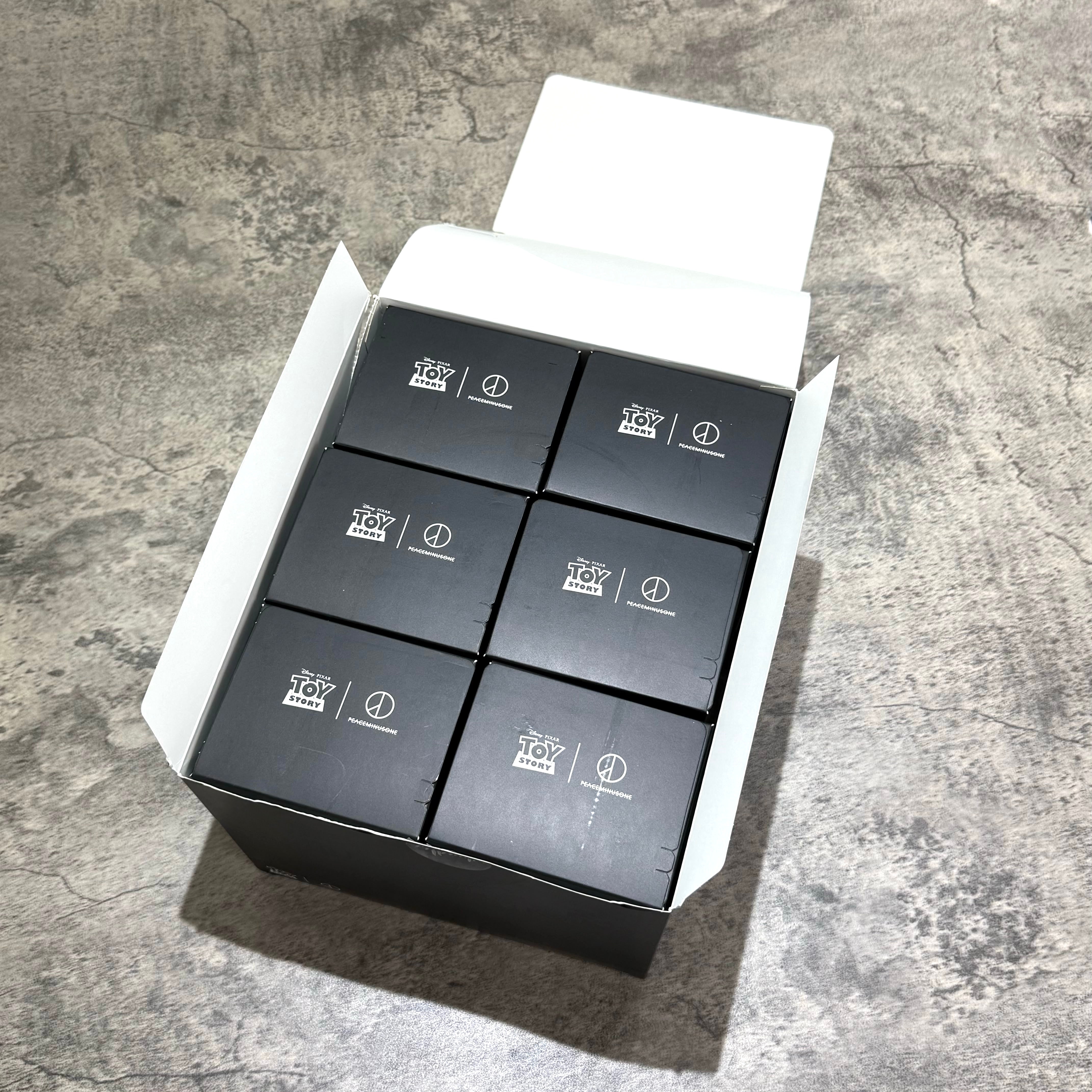 PEACEMINUSONE x Toy Story The First Fan blind box key rings displayed in an opened box.