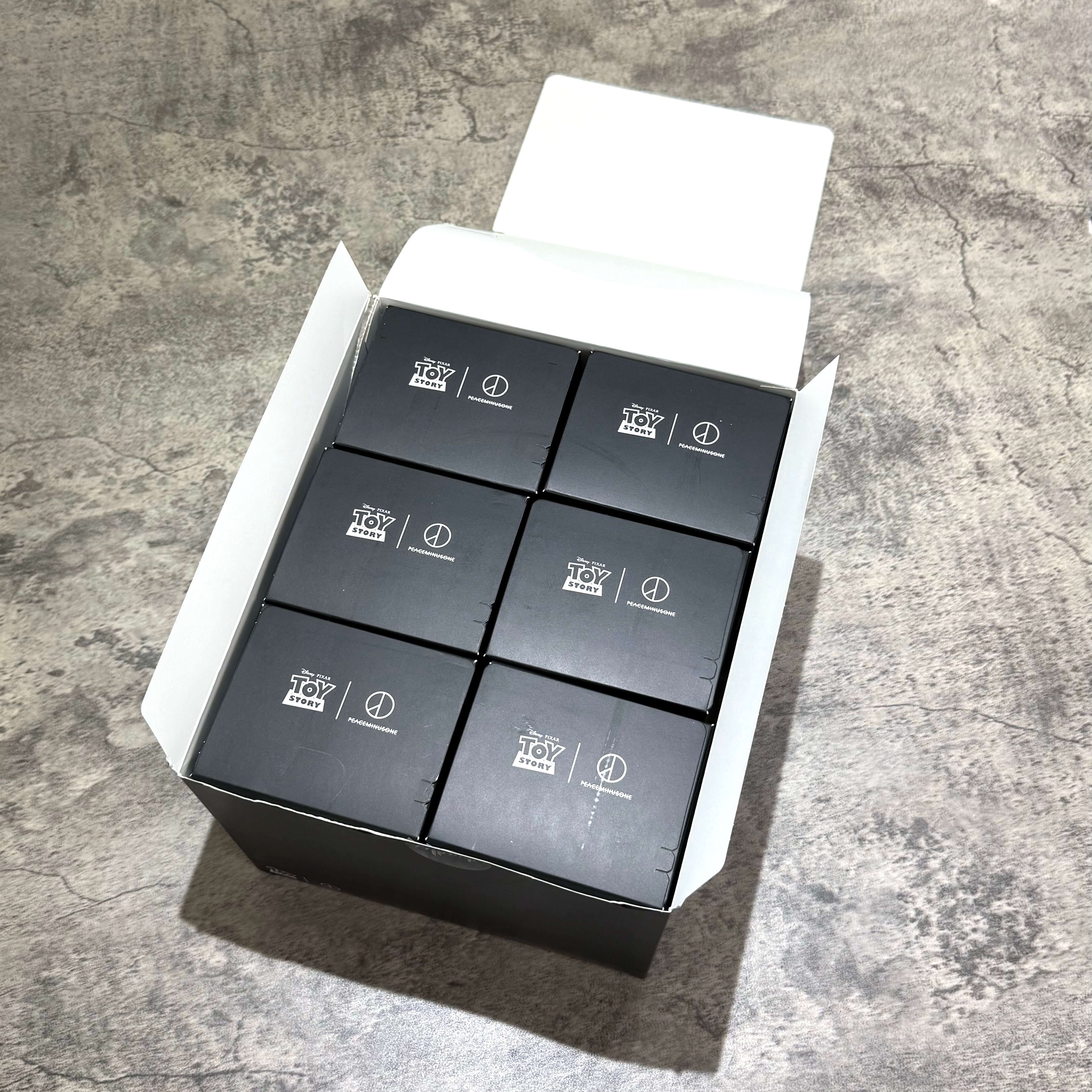 PEACEMINUSONE x Toy Story The First Fan blind box key rings displayed in an opened box.