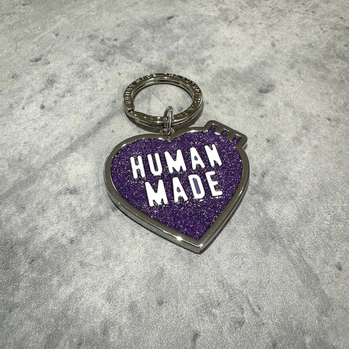 Human Made Store Exclusive Heart Keychain in purple glitter design on a gray background.