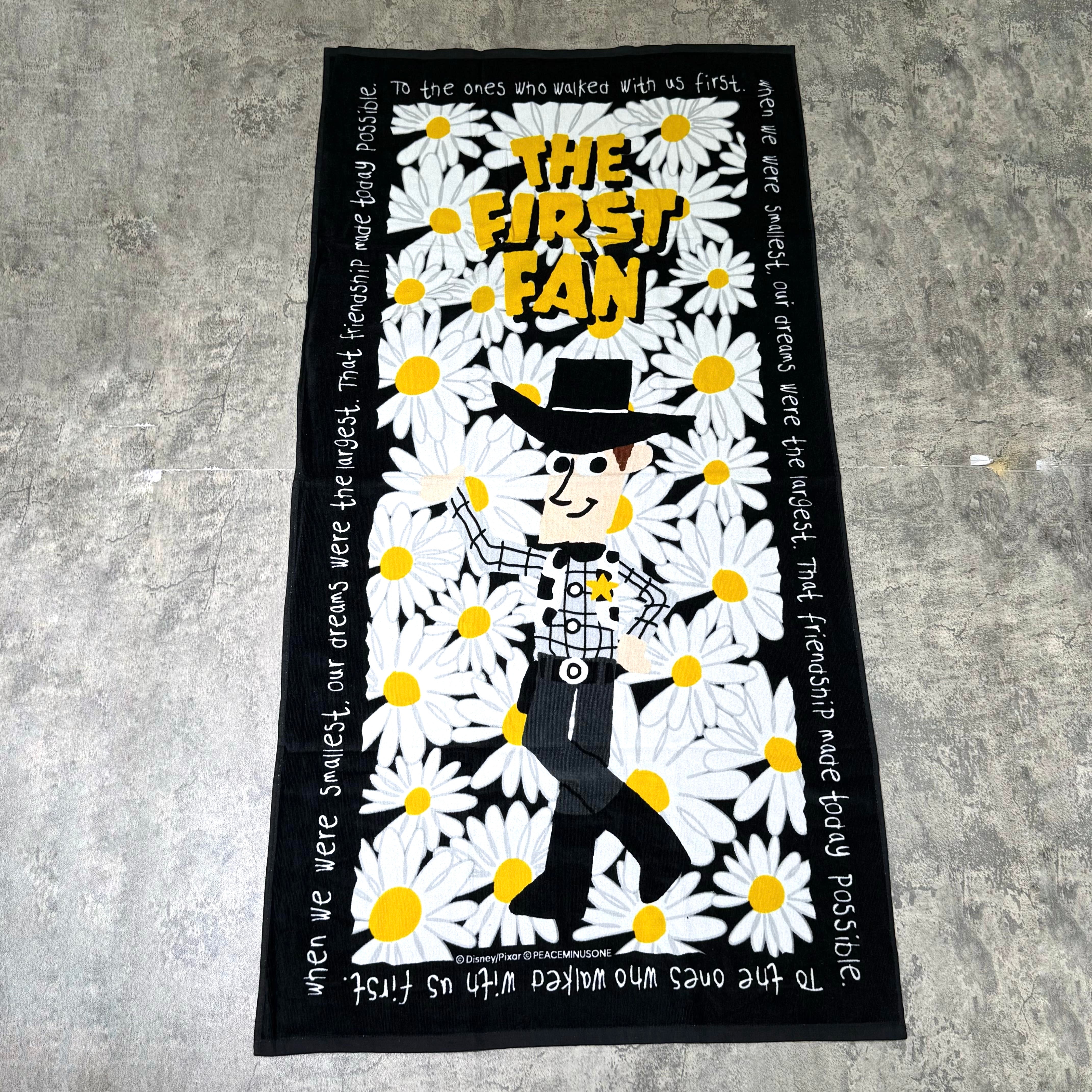 PEACEMINUSONE x Toy Story The First Fan beach towel featuring a character surrounded by daisies.