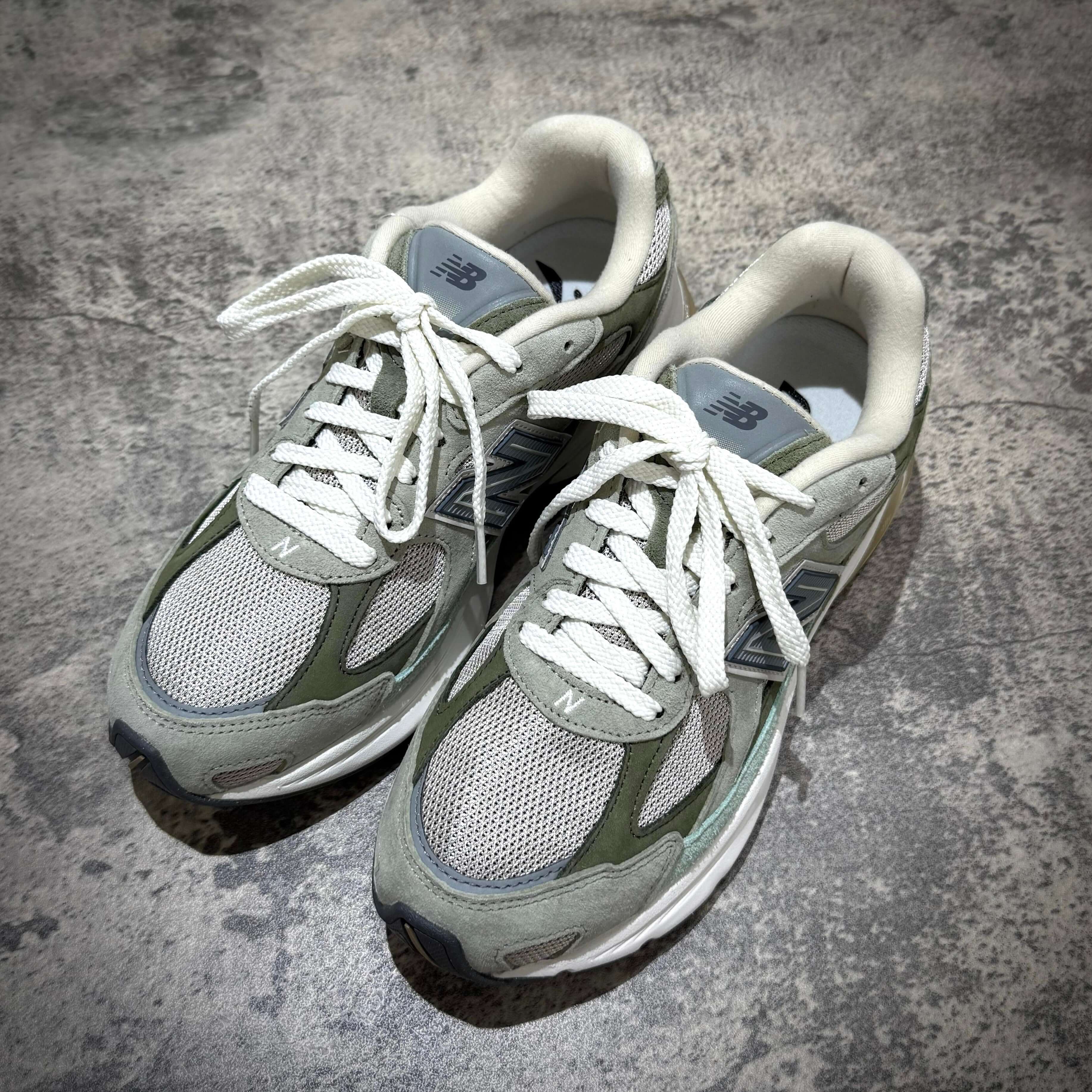 New Balance U20105K7 Wasabi Green sneakers with grey and green accents and white laces on a textured surface.