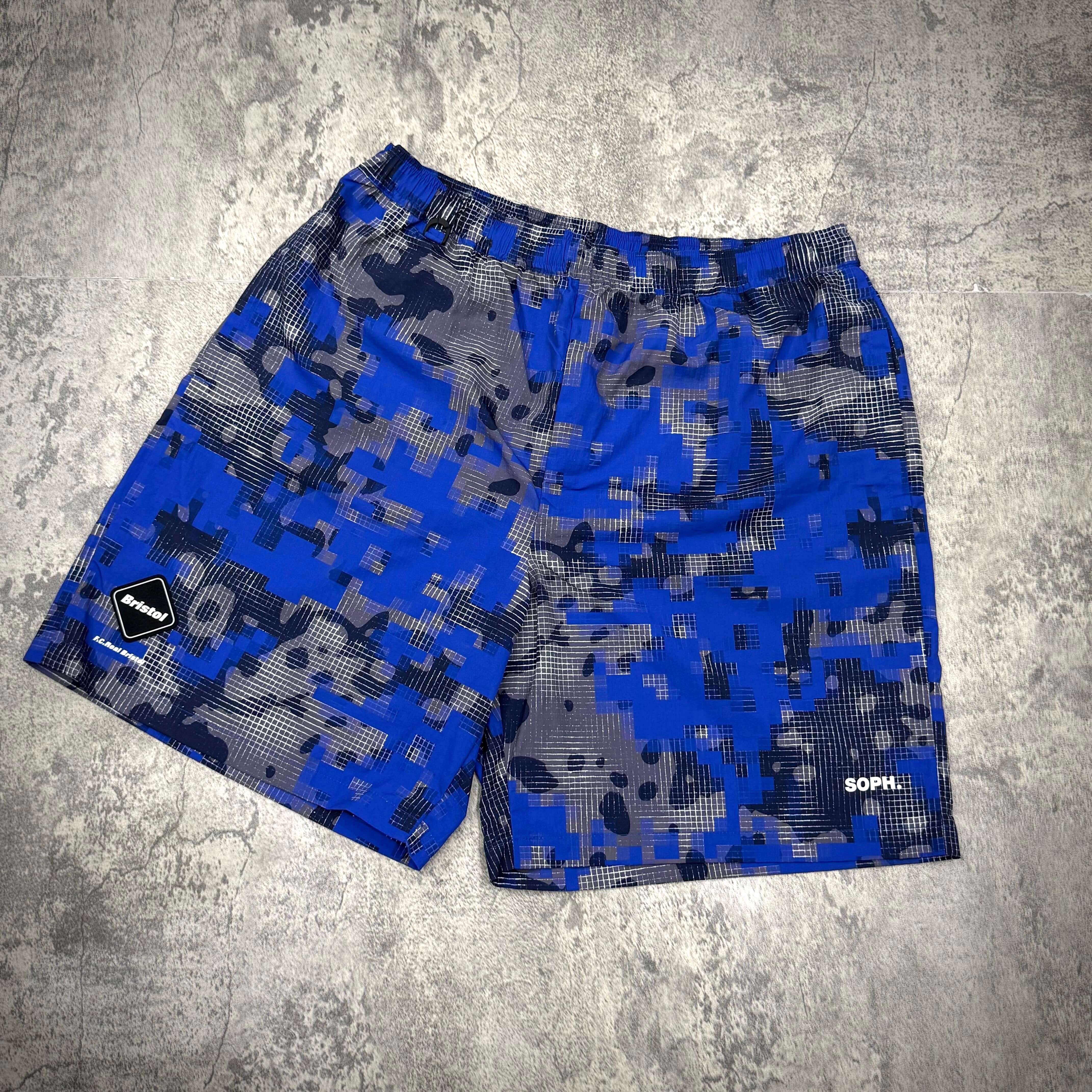 Fragment x FCRB Camouflage Nylon Shorts in blue and gray camouflage pattern on a textured background