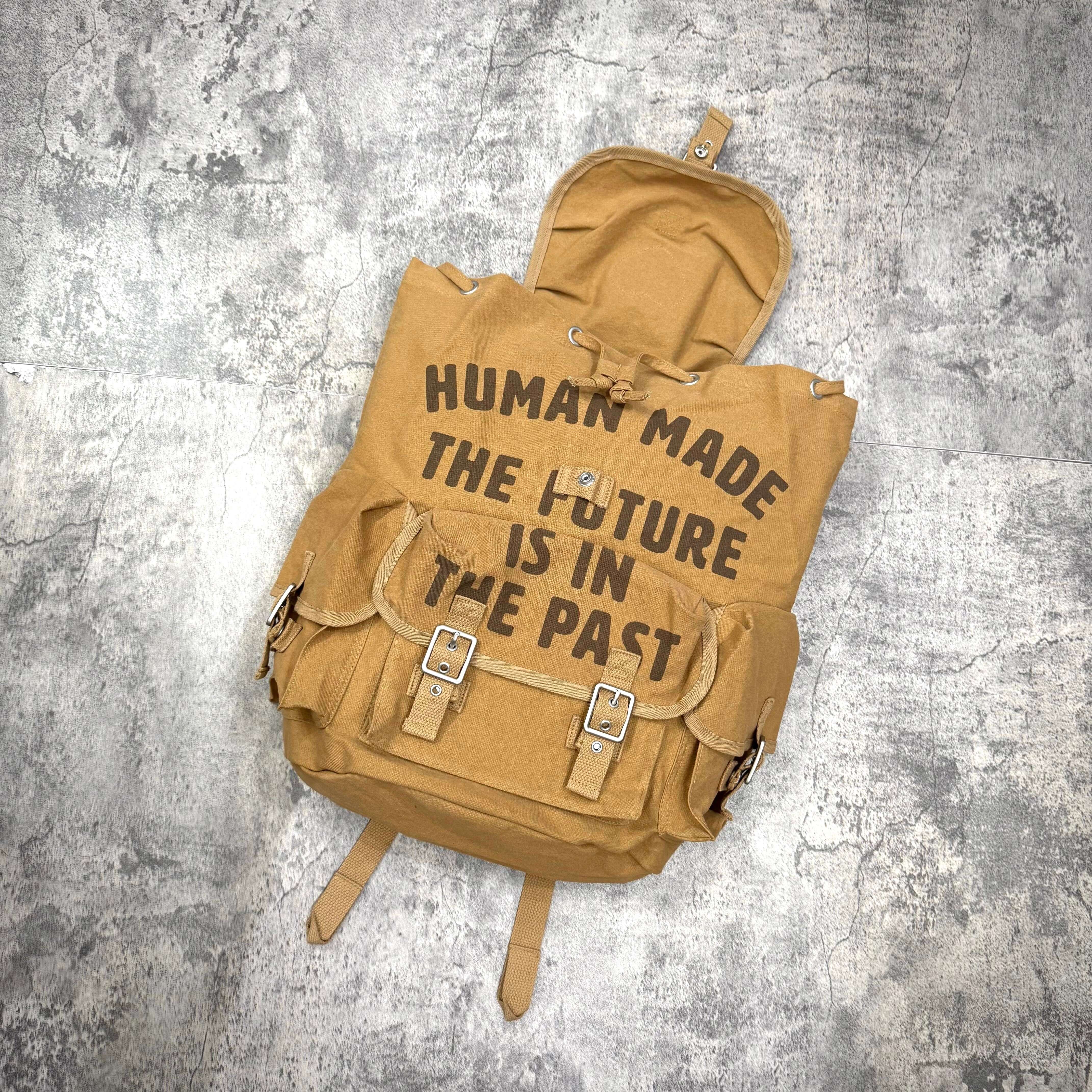 Human Made Hunting Backpack in tan color with bold text design, perfect for outdoor adventures.