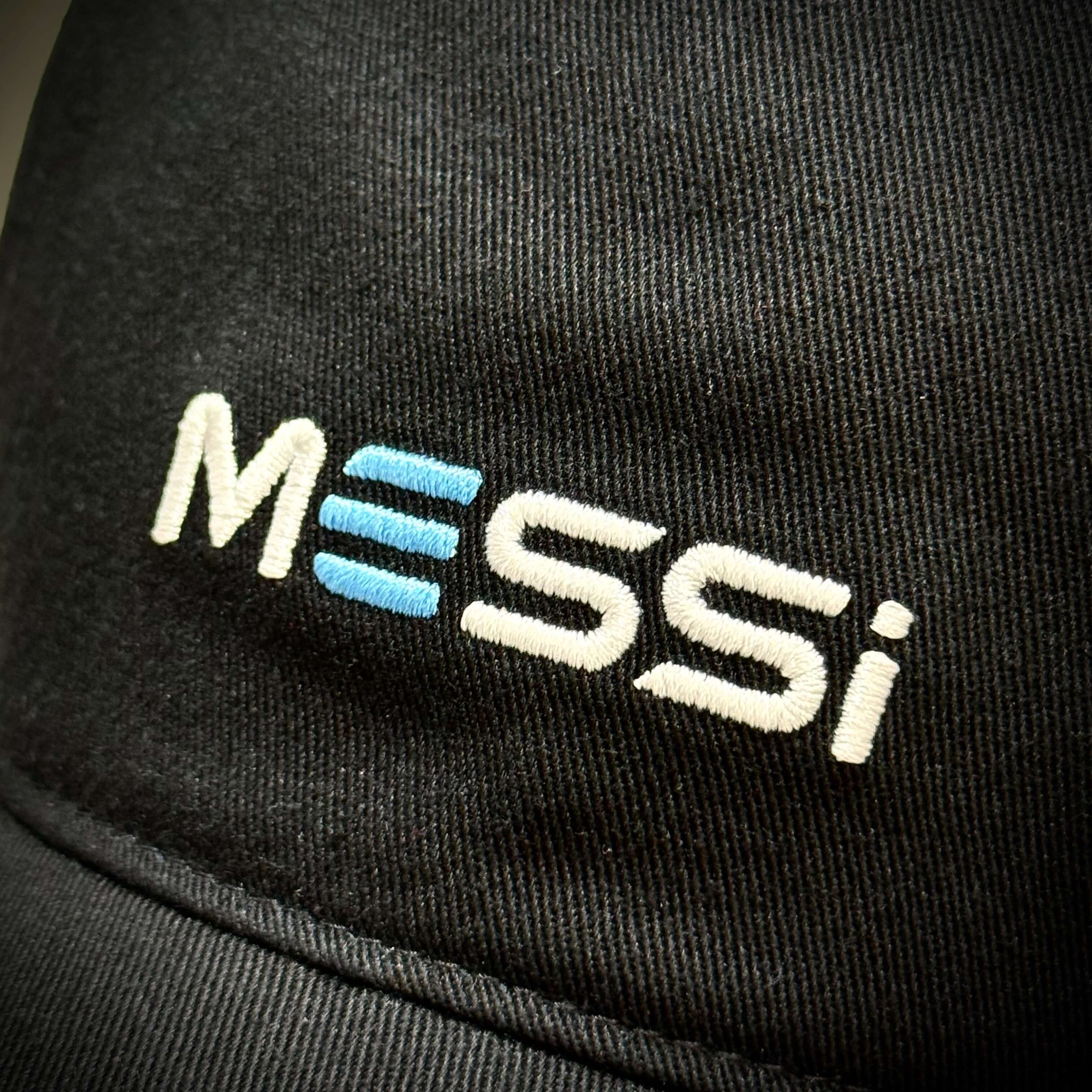 Close-up of KITH x MESSI for adidas Football Trcuker Hat 6 Panel Cap showing embroidered Messi logo on black fabric.