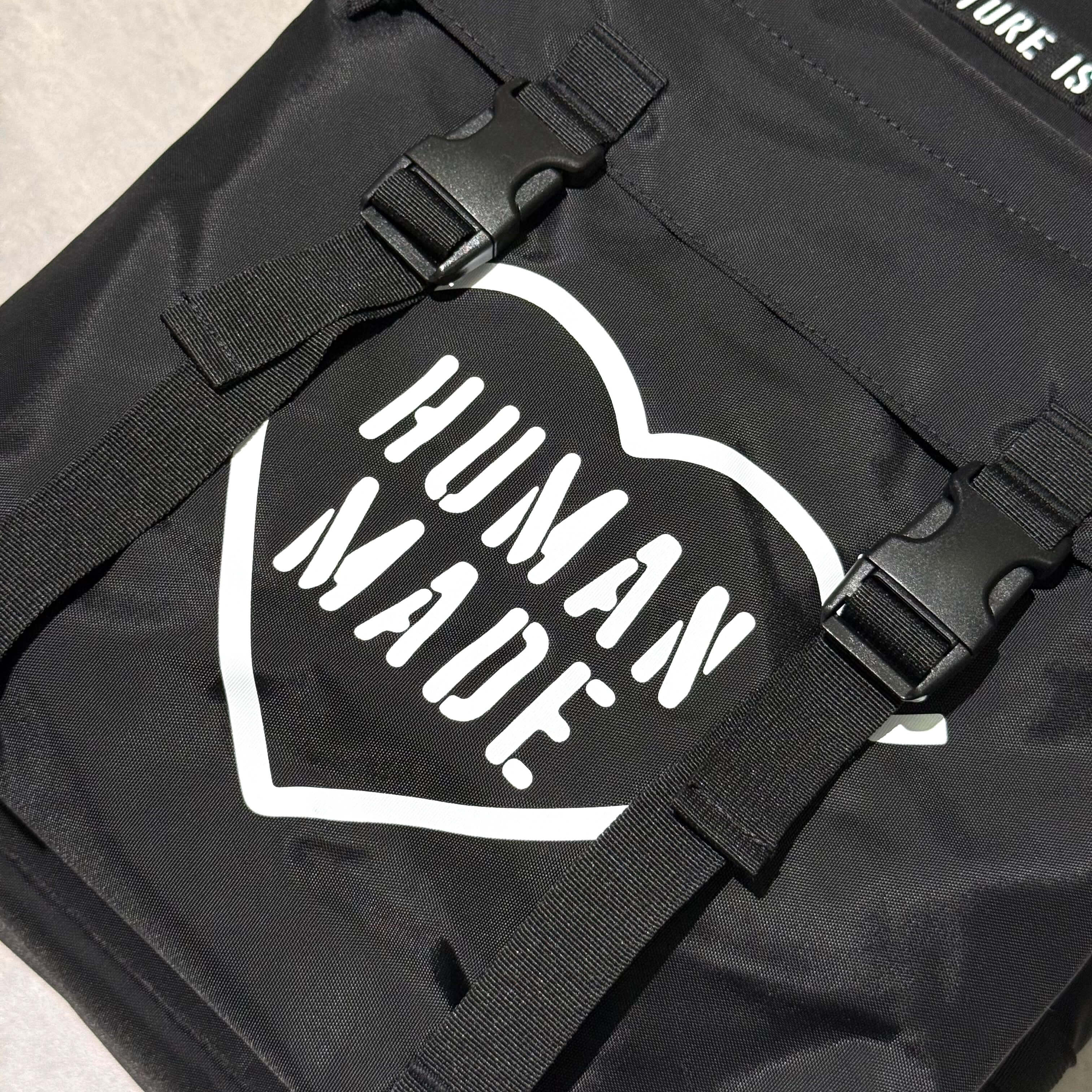 Close-up of Human Made Military Backpack featuring bold 'HUMAN MADE' logo on black fabric design.