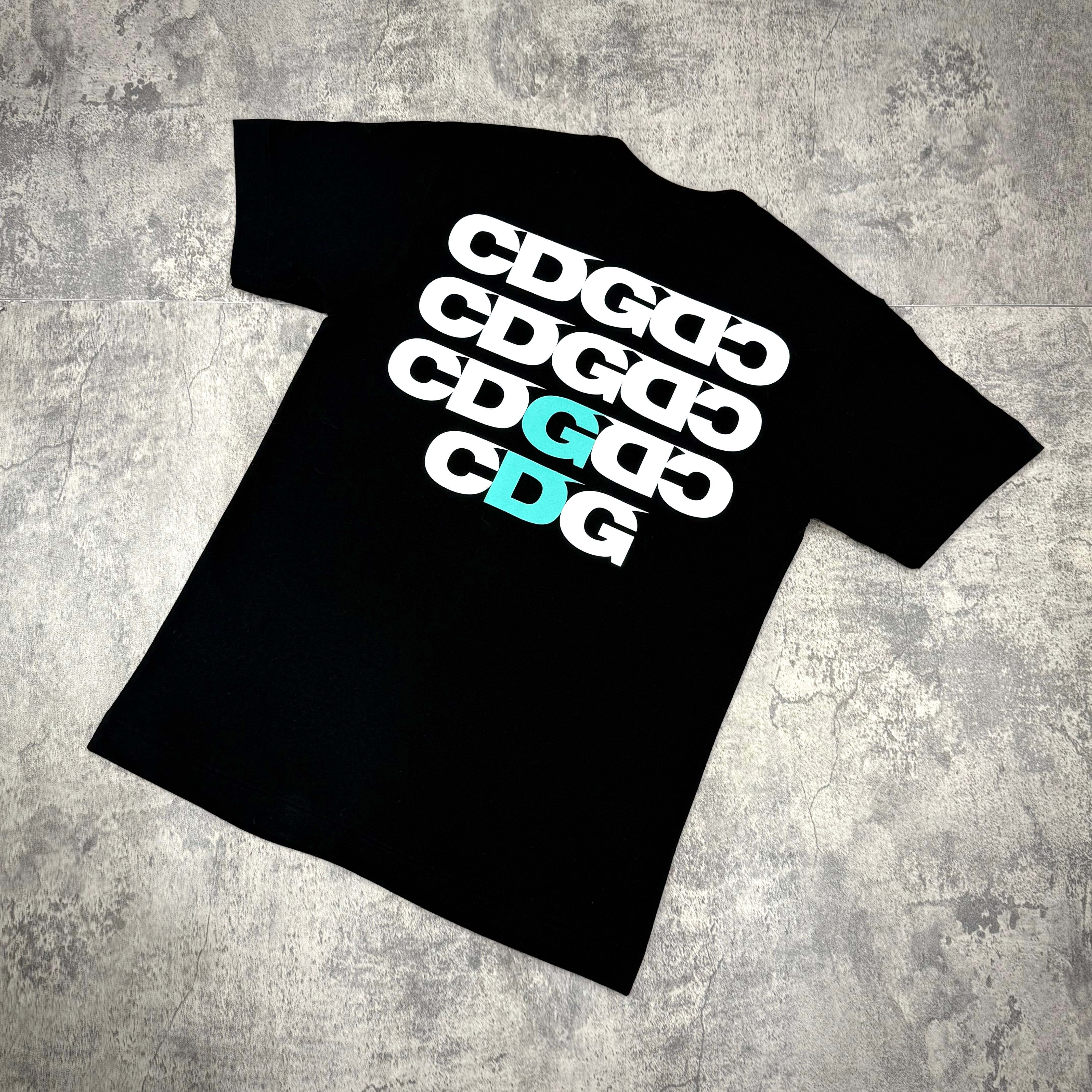 CDG x G-DRAGON Ubermensch Symbol Tee featuring bold CDG logos in white and aqua on a black background.