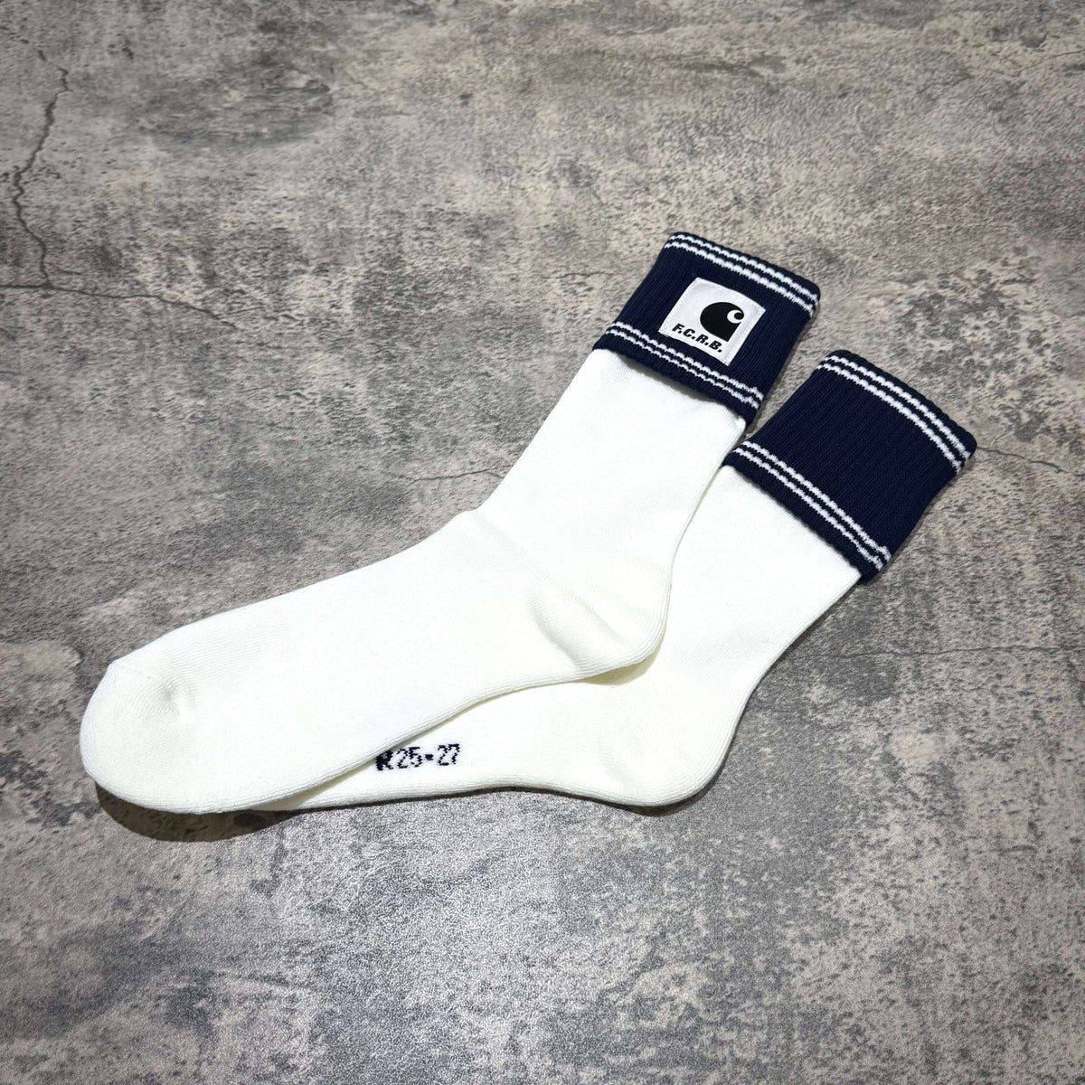 Carhartt WIP x F.C.Real Bristol Cuff Socks displaying white and navy color design with logo on a gray background