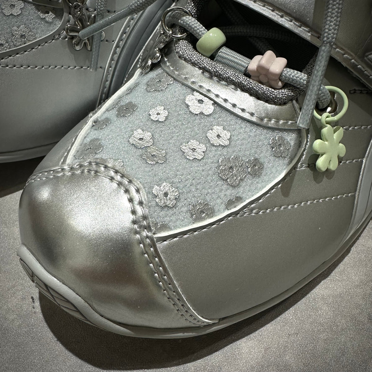 Close-up of Cecilie Bahnsen x Asics Gel-Kinetic FR - Pure Silver, showcasing floral details and shiny materials.