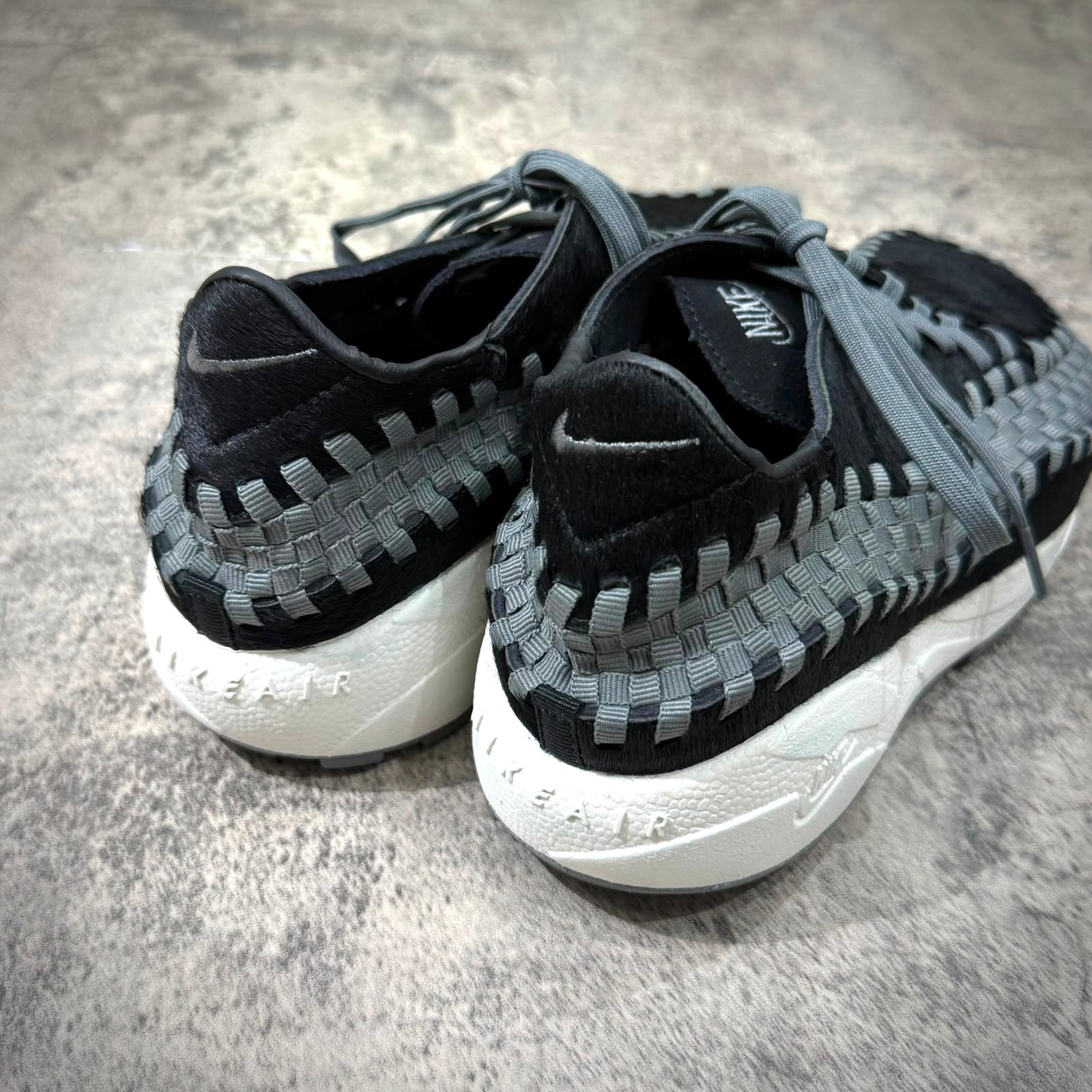 Nike Air Footscape Woven Black Smoke Grey rear view showcasing woven design and color details.