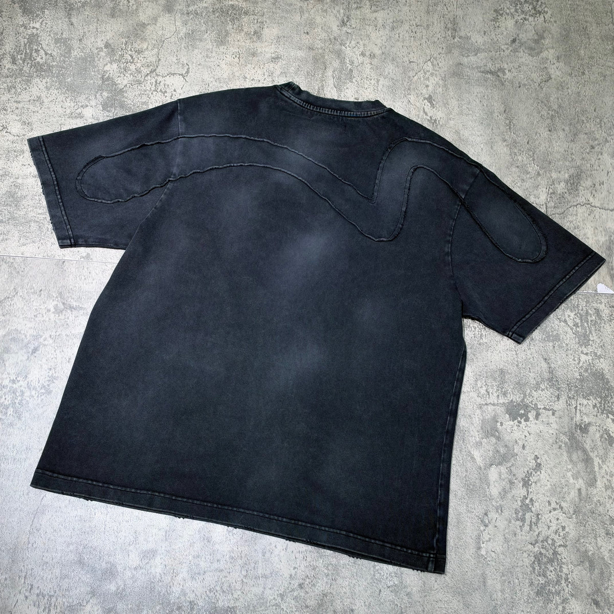 Back view of Evisu x Mastermind Japan x Roarguns Tee showcasing unique stitching design on a black fabric.