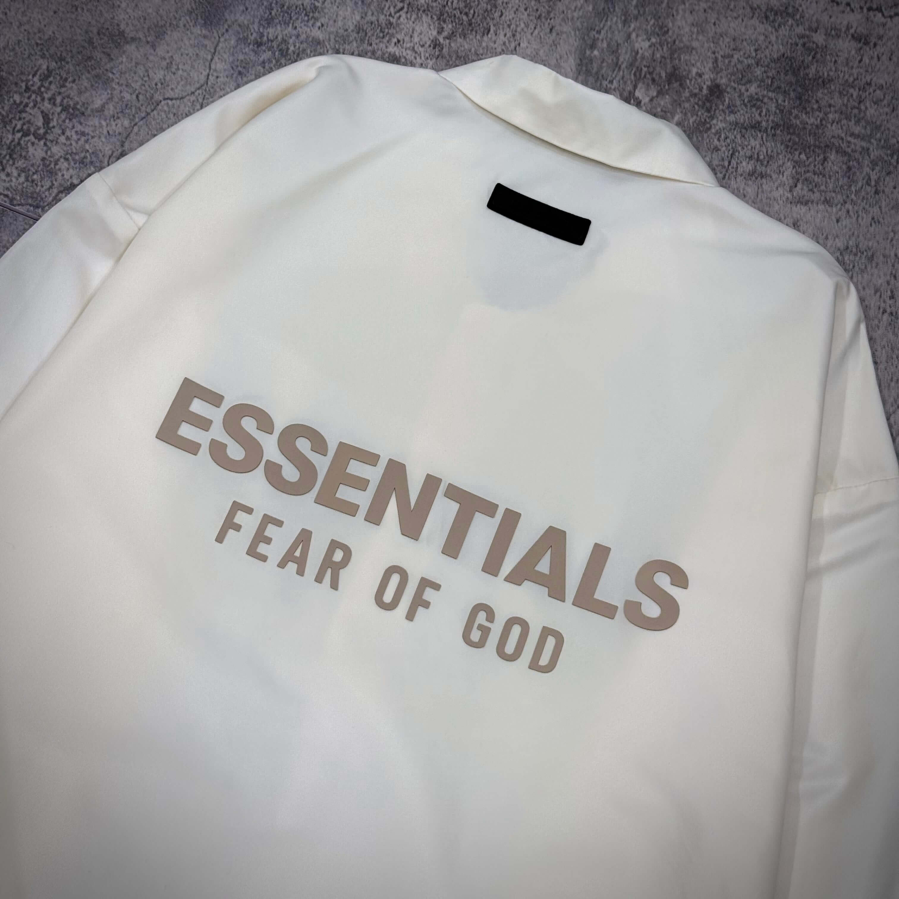 現貨 FOG Essentials Coaches Jacket FW23 - Cloud Dancer 背面設計,展示 ESSENTIALS FEAR OF GOD 字樣