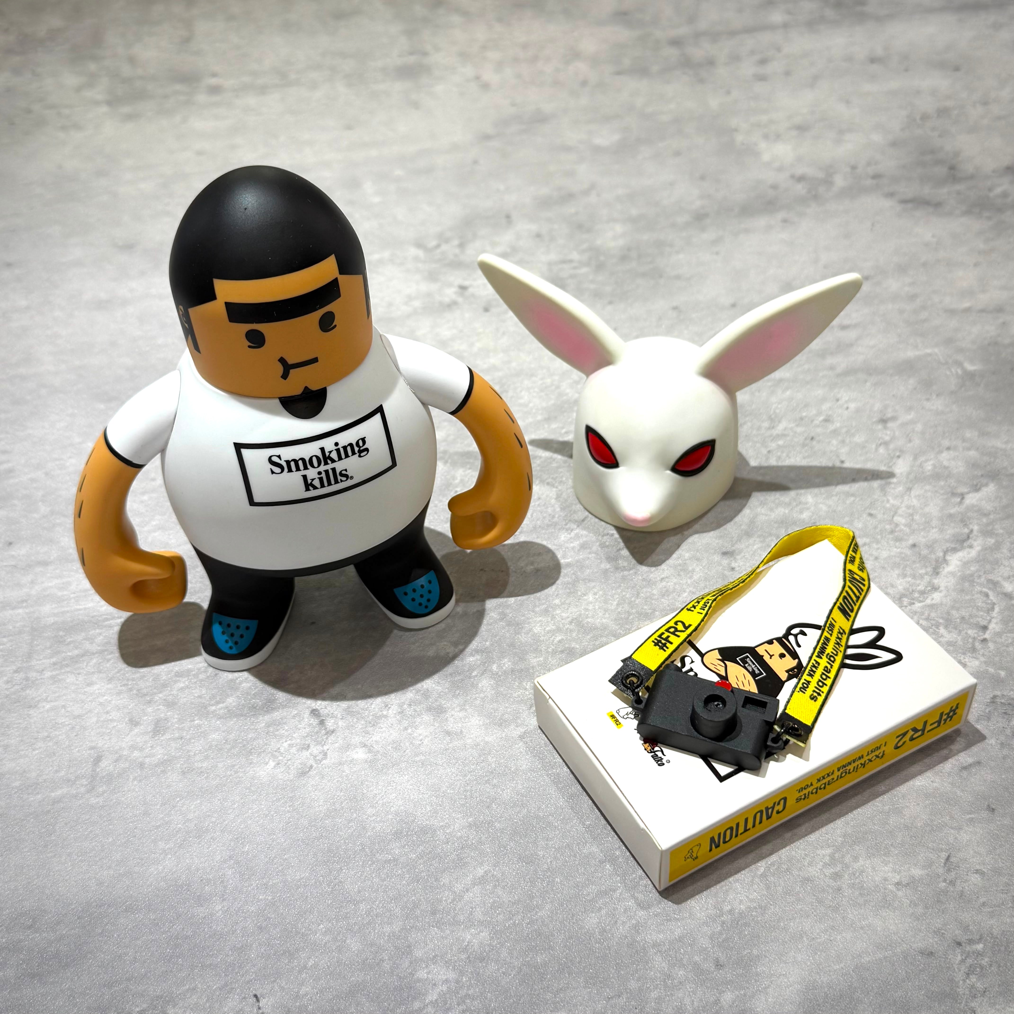 FR2 Fatko X FR2 Figure Doll - White/Black alongside accessories and bunny figure on a gray background