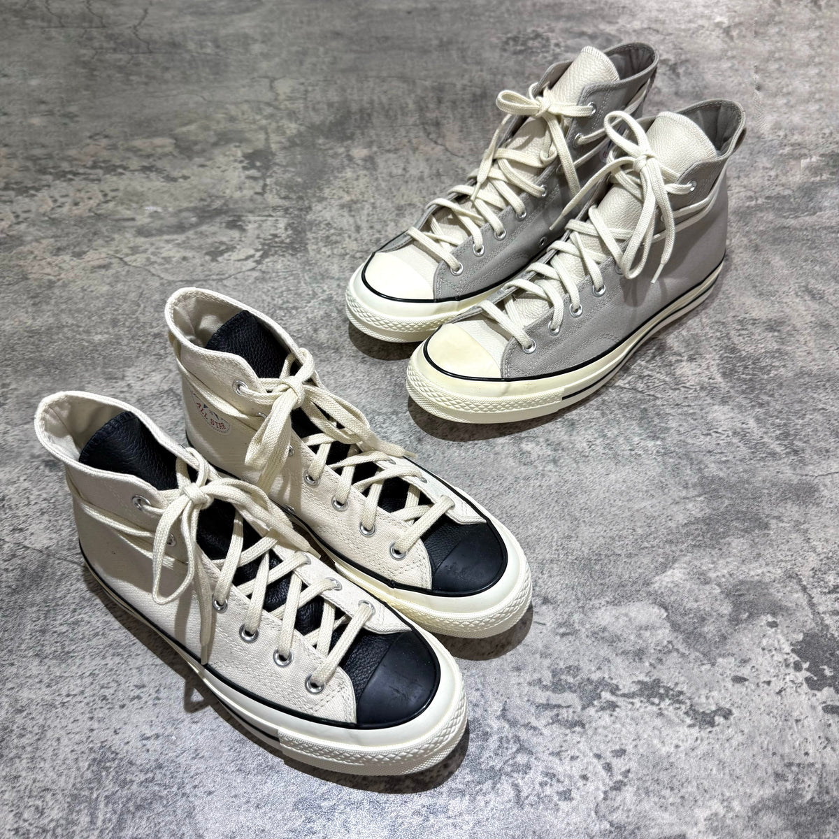 Fear Of God Essentials x Converse Chuck 70s Hi - White and Grey high-top sneakers displayed on a textured surface.