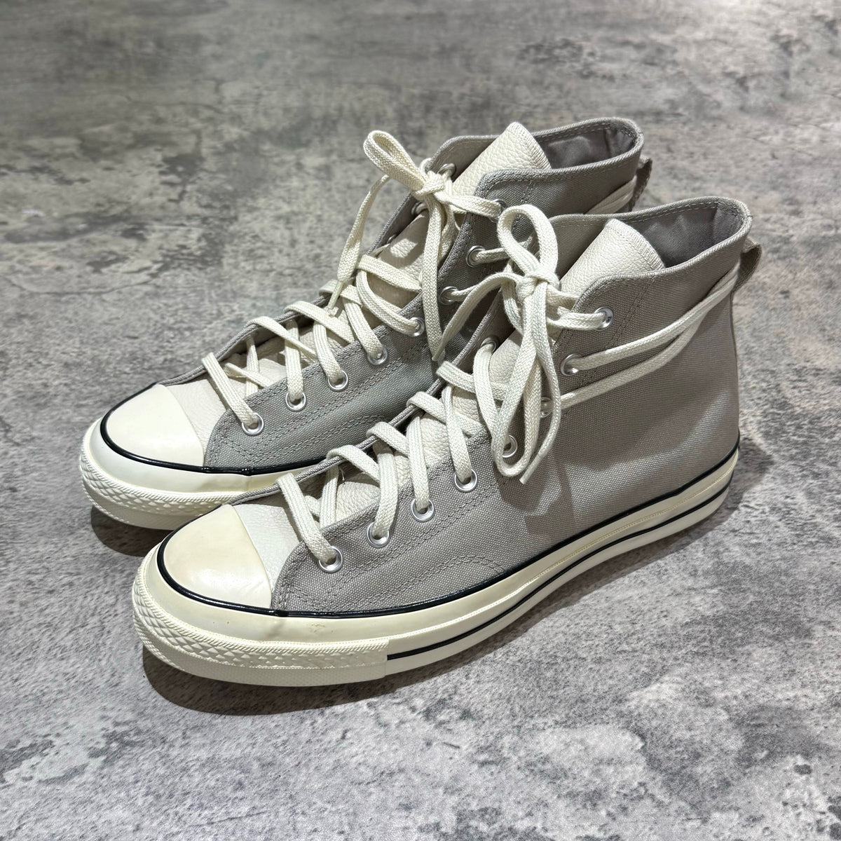 Fear Of God Essentials x Converse Chuck 70s Hi - White / Grey sneakers displayed on a textured surface.