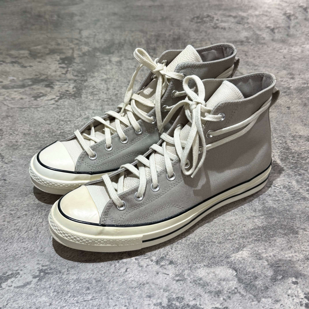 Fear Of God Essentials x Converse Chuck 70s Hi - White / Grey sneakers displayed on a textured surface.