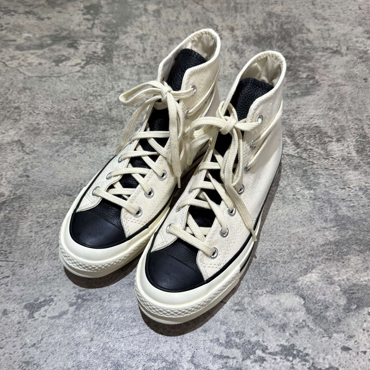 Fear Of God Essentials x Converse Chuck 70s Hi - White / Grey sneakers on a textured background.