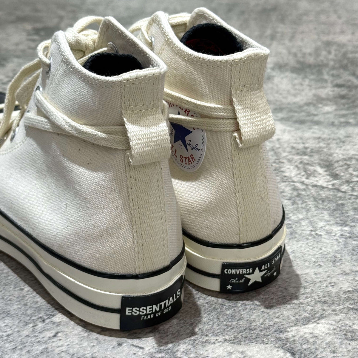 Fear Of God Essentials x Converse Chuck 70s Hi showing the back view of white canvas shoes with black branding
