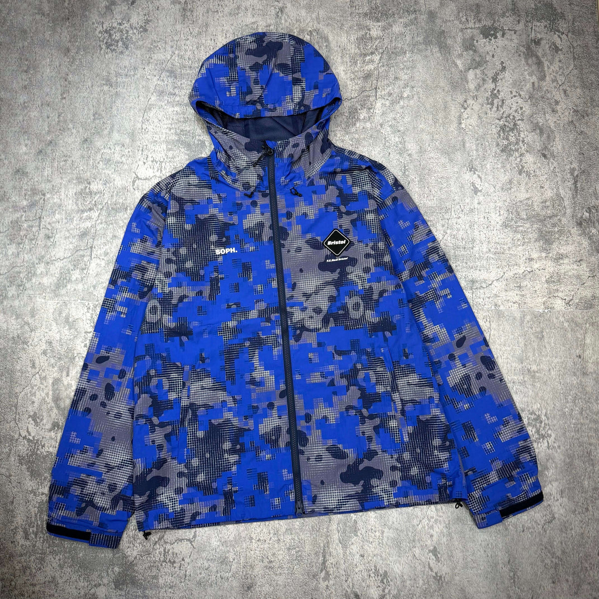 Fragment x F.C.Real Bristol Camouflage Nylon Blouson in blue camouflage design with hood.