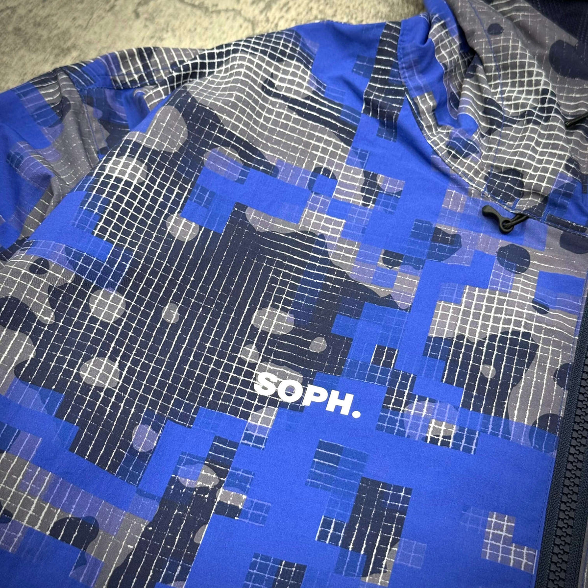 Fragment x F.C.Real Bristol Camouflage Nylon Blouson showcasing a vibrant blue camouflage design with SOPH. branding.
