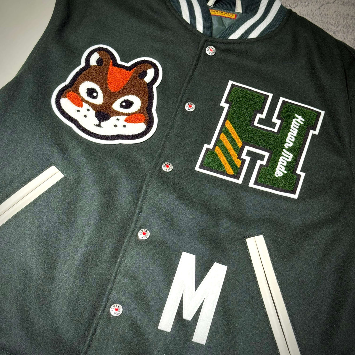 HUMAN HOPE Varsity Jacket HUMAN MADE x j-hope of BTS featuring embroidered graphics and green fabric.