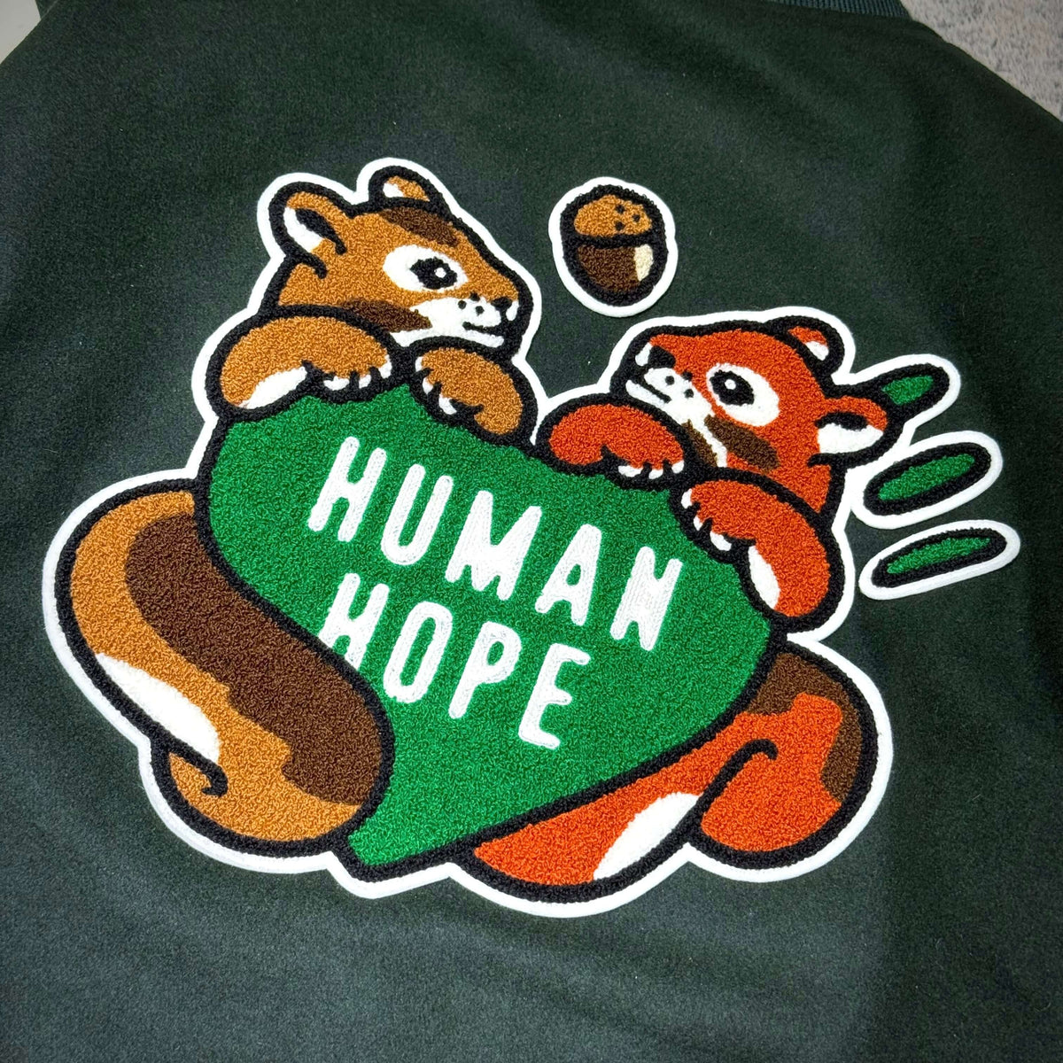 Image featuring the HUMAN HOPE Varsity Jacket HUMAN MADE x j-hope of BTS with playful animal graphics.