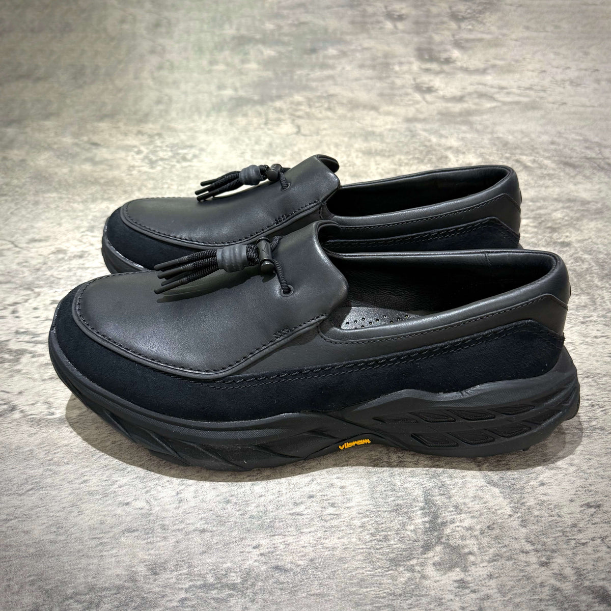 Hoka Speed Loafers - Black 1162170-BBLC displayed from the side on a textured surface.