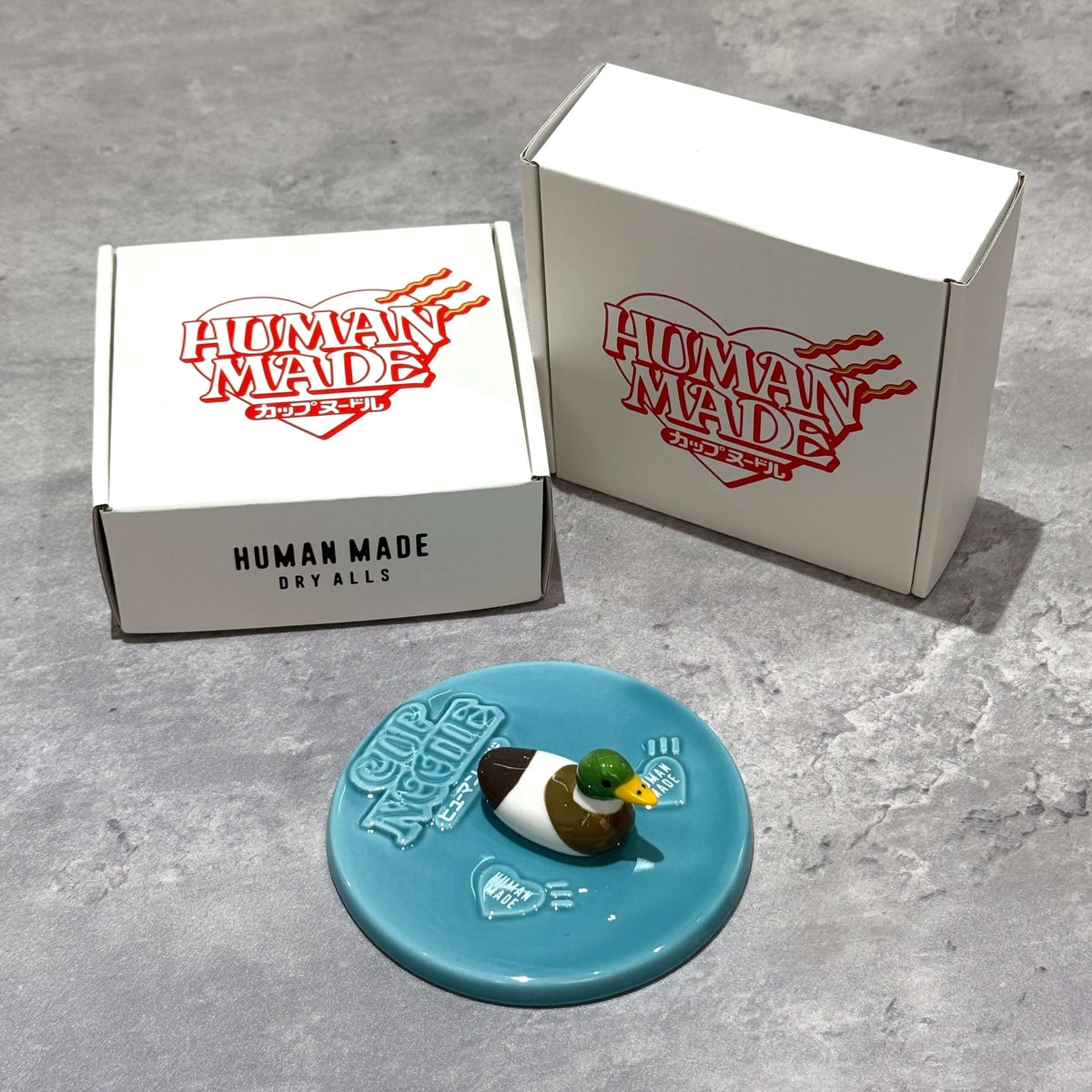 Human Made Lid Holder featuring a duck design on a blue base with branded packaging.