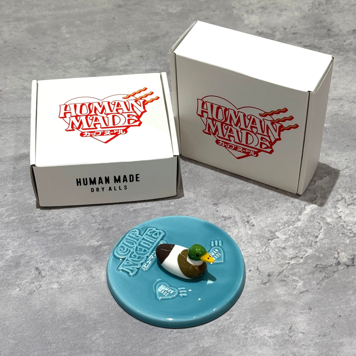 Human Made Lid Holder featuring a duck design on a blue base with branded packaging.