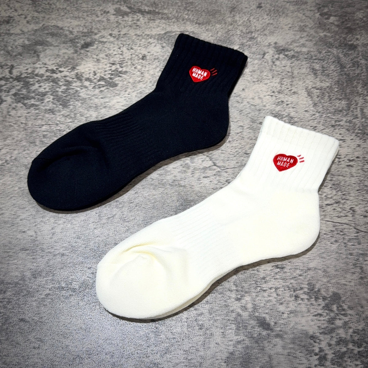 Human Made Pile Short Socks HM00GD009 in black and white colors displayed on a textured surface.