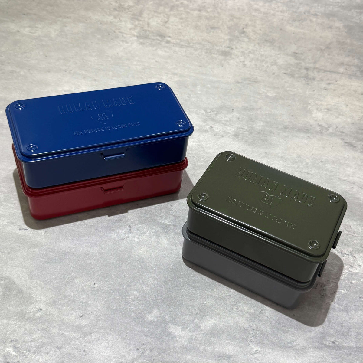 Human Made Steel Tool Box in blue and green with a vintage industrial design on a gray surface.
