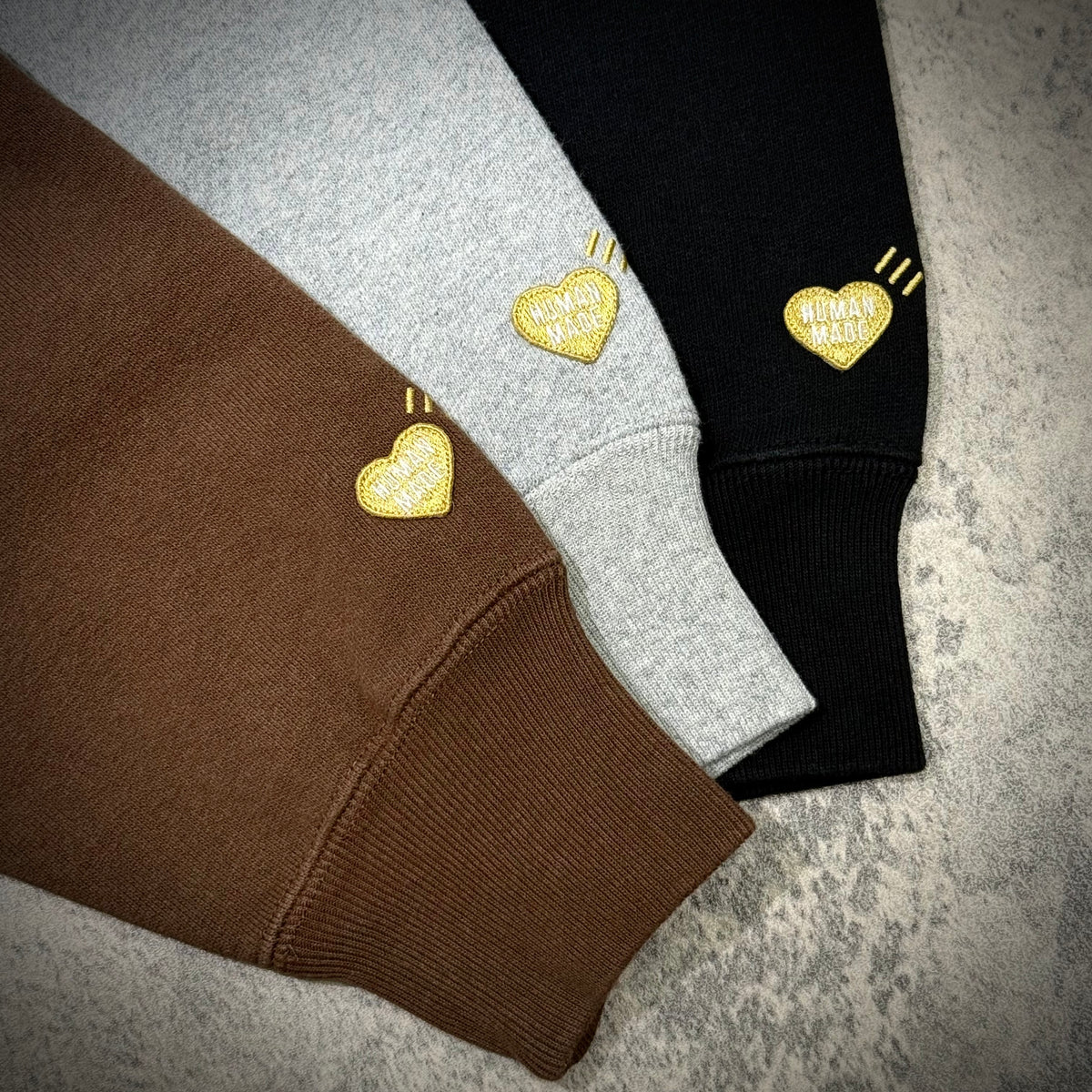 Human Made Tokyo Exclusive Lion Heavyweight Hoodie color options in brown, grey, and black with heart logo details.