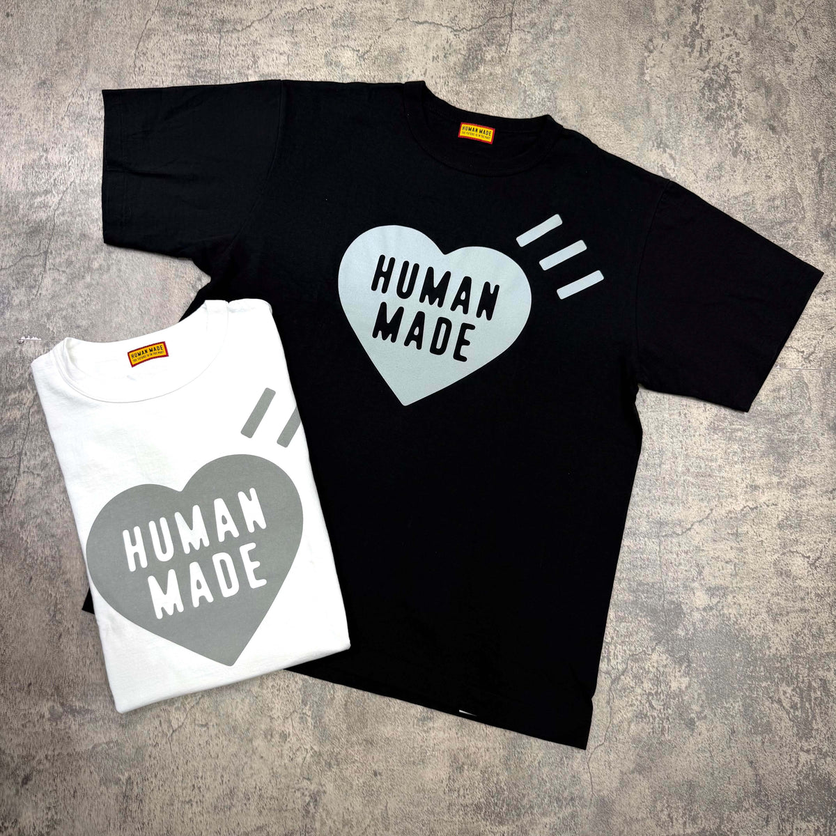 Human Made Sapporo Exclusive Heart Logo Tee in black and white displayed on a textured background.