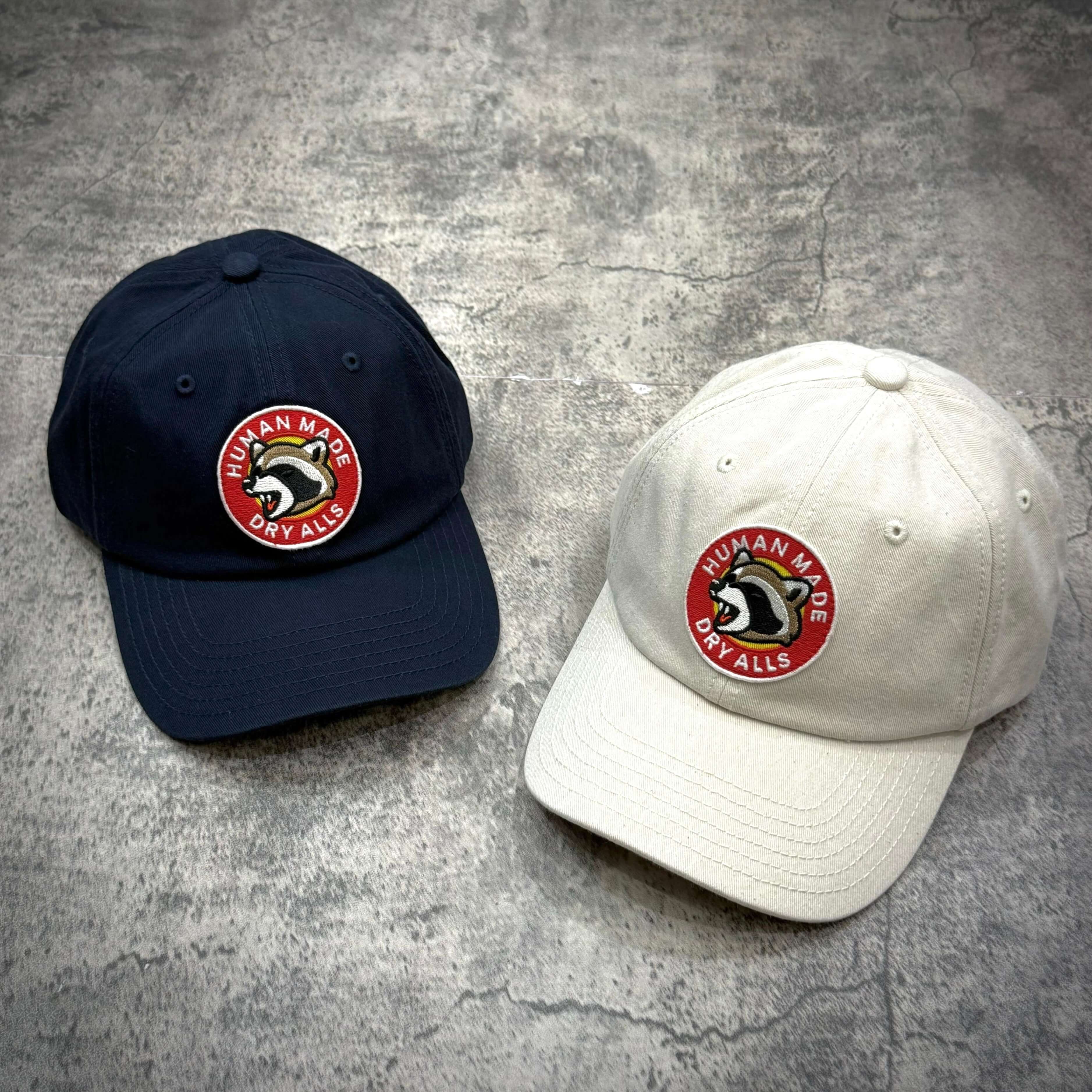 Human Made Jamsil Exclusive 6 Panel Twill Raccon Cap in navy and white color options on a textured background