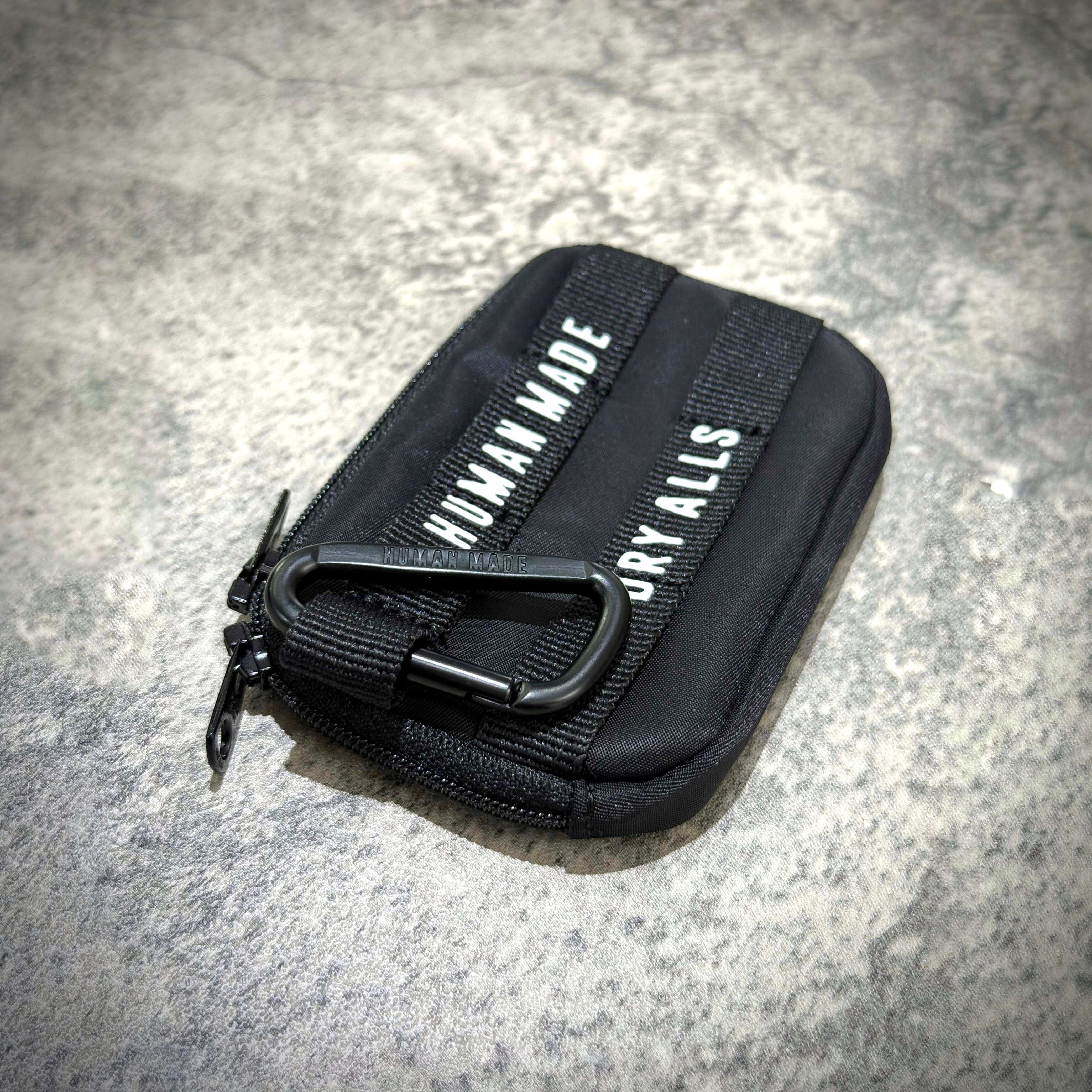 Human Made Military Card Case featuring black material and zipper with a carabiner clasp.