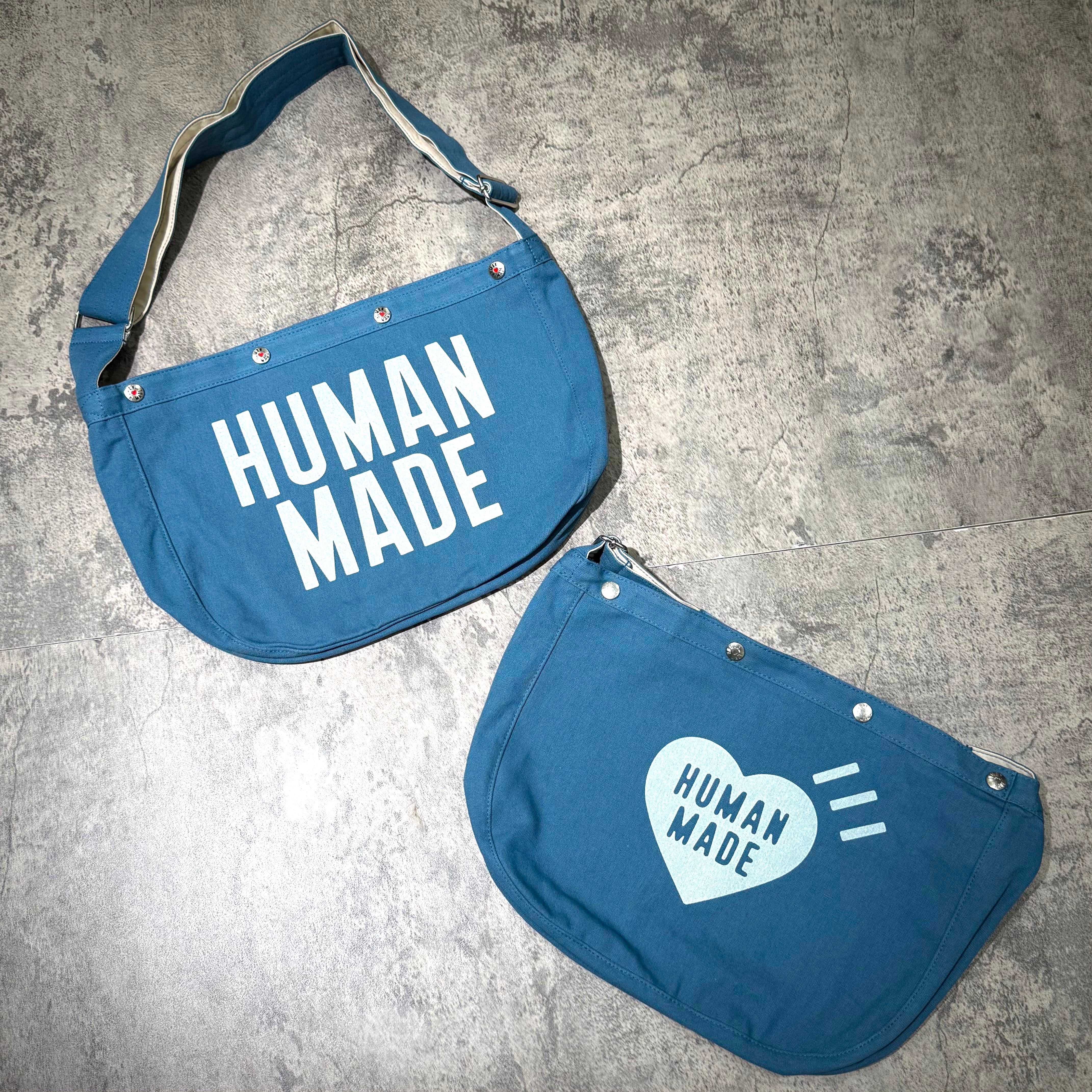 Human Made Paper Boy Bag featuring blue fabric and white text design, showcasing the brand's unique style.