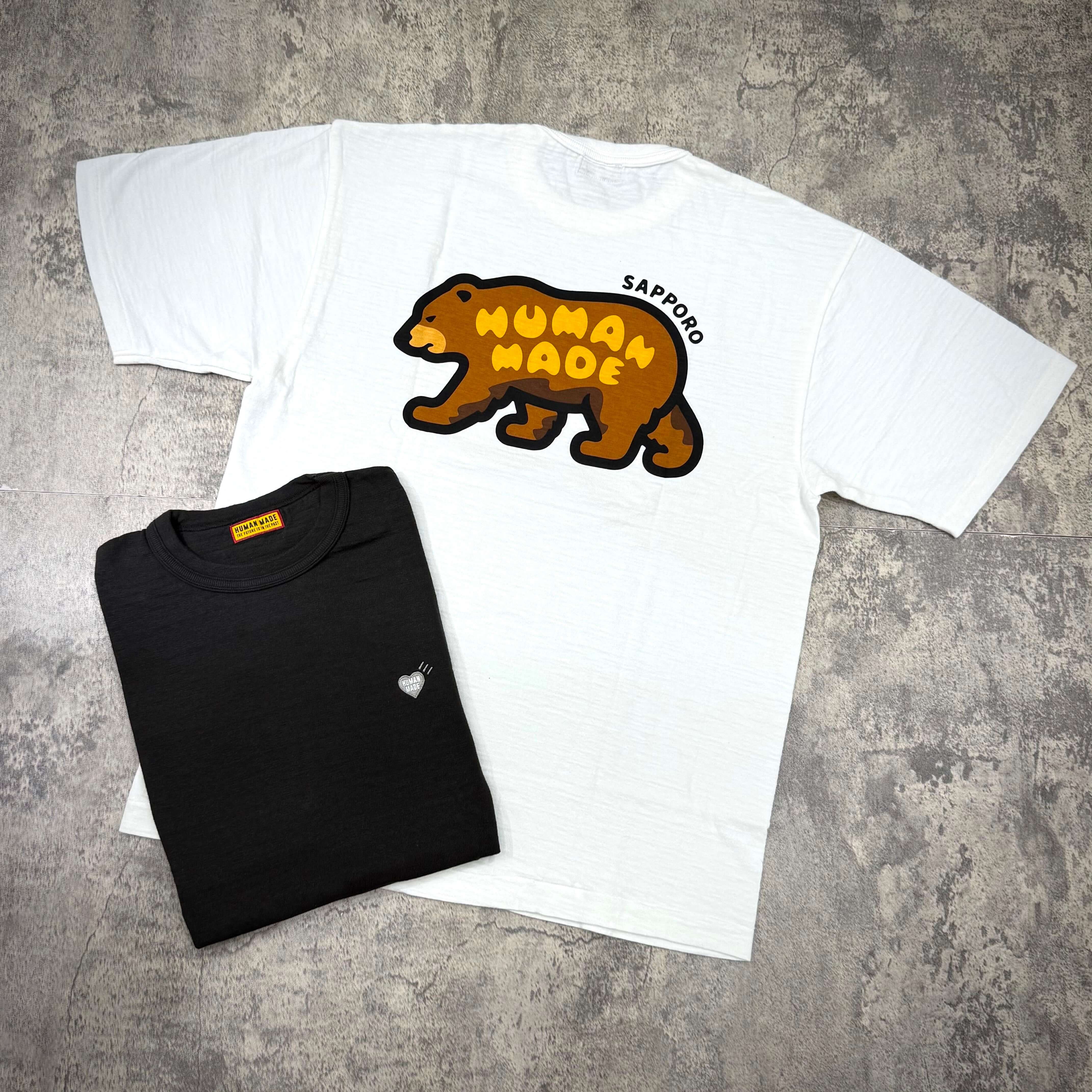 Human Made Sapporo Exclusive Bear Back Logo Tee displayed alongside a black tee, highlighting the bear logo design.