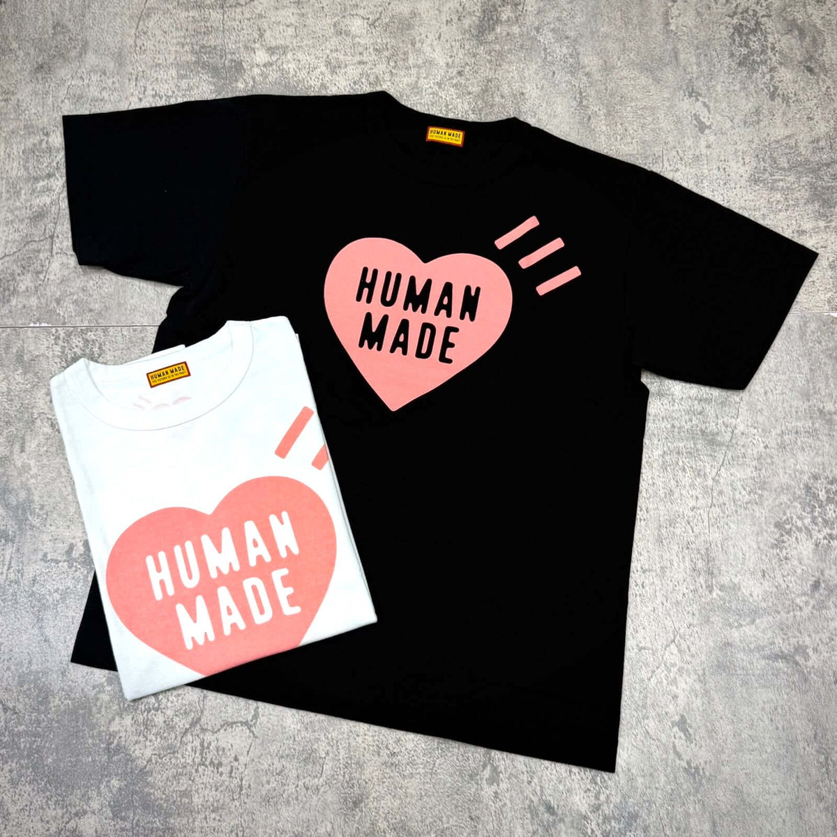 Human Made Seoul Exclusive Heart Logo Tee in black and white color options, featuring a heart logo and text.