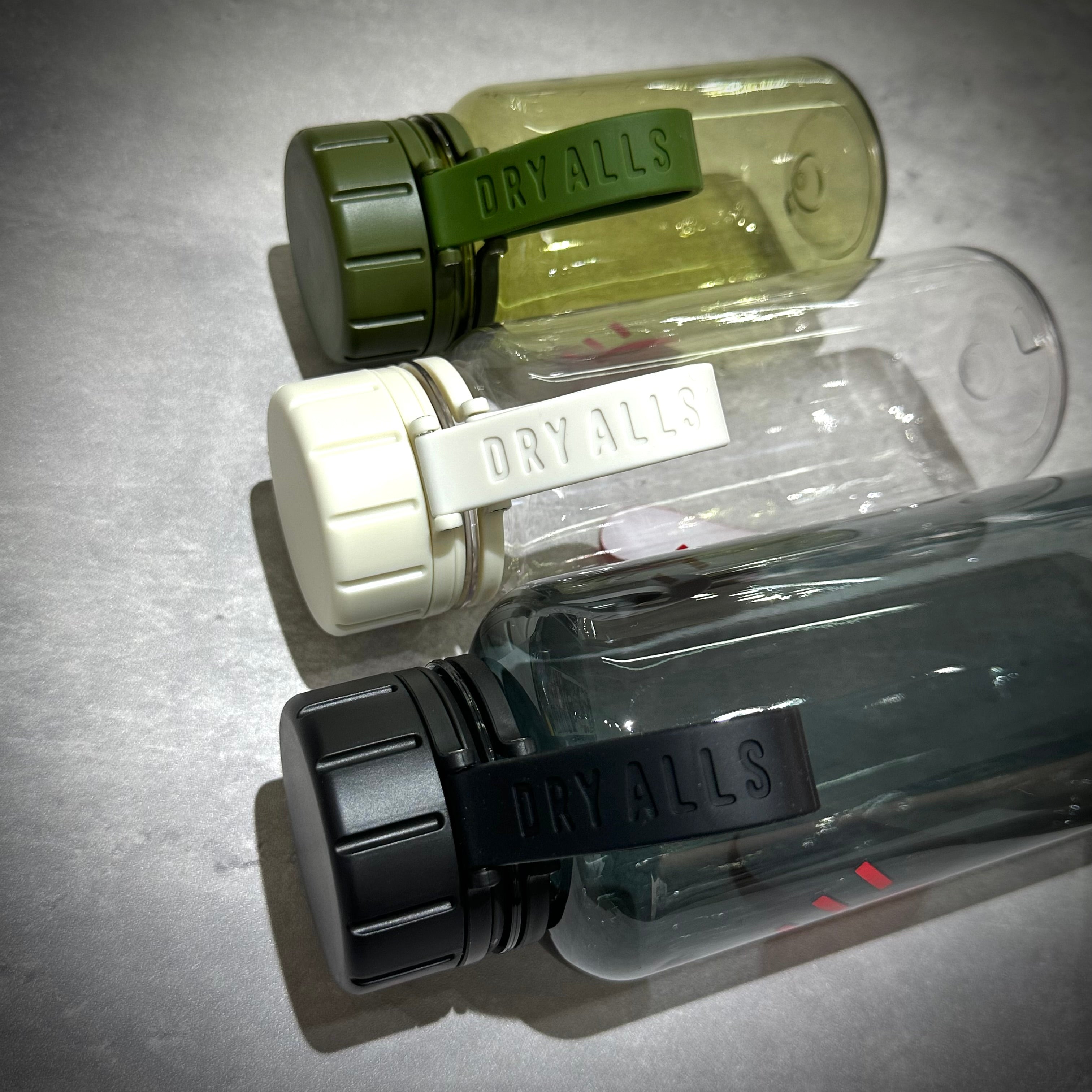 Human Made Water Bottle in three color variations: green, white, and black with dry all straps.